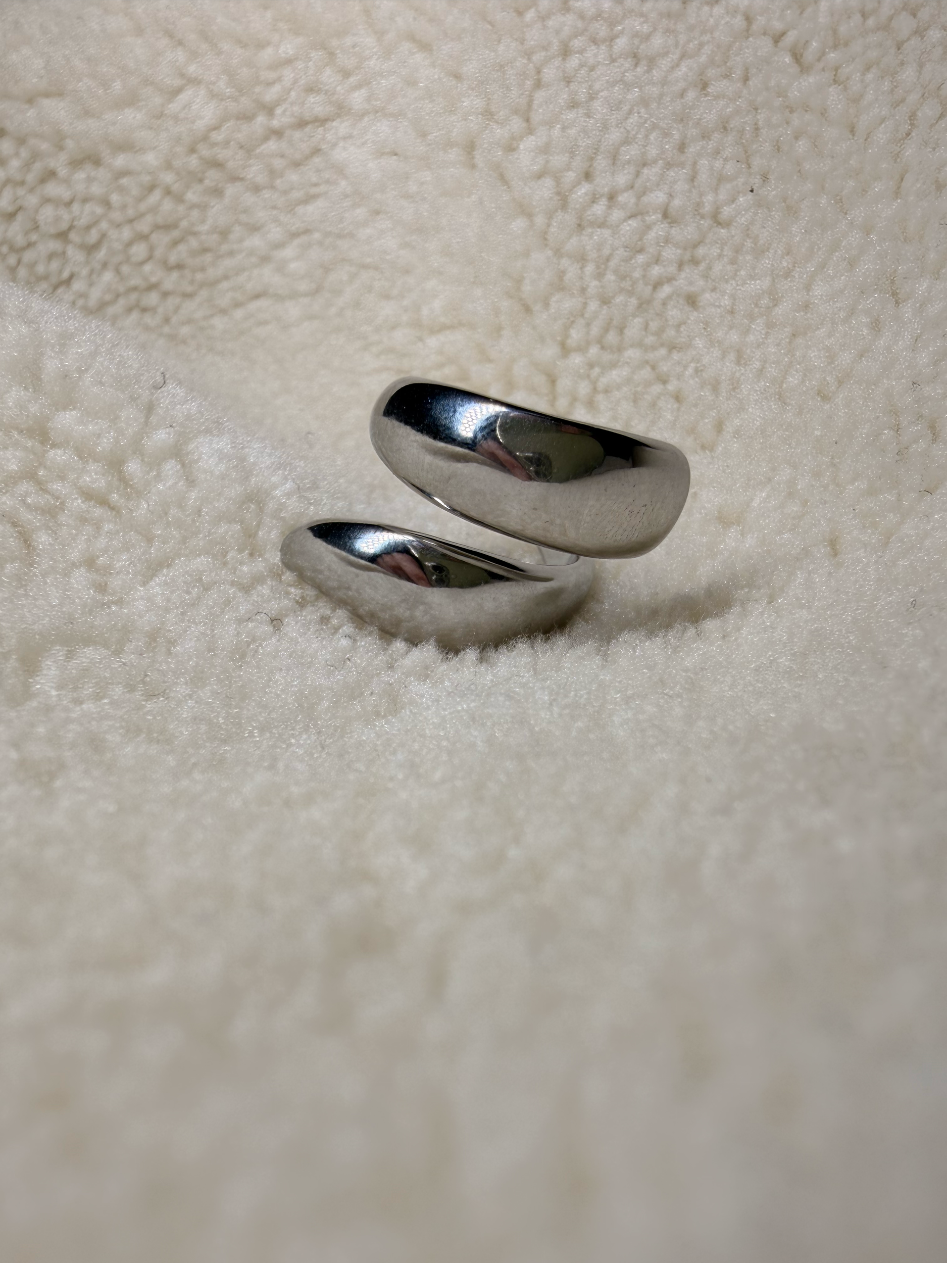 Deux alliances en argent posées sur une surface en tissu blanc doux et duveteux.