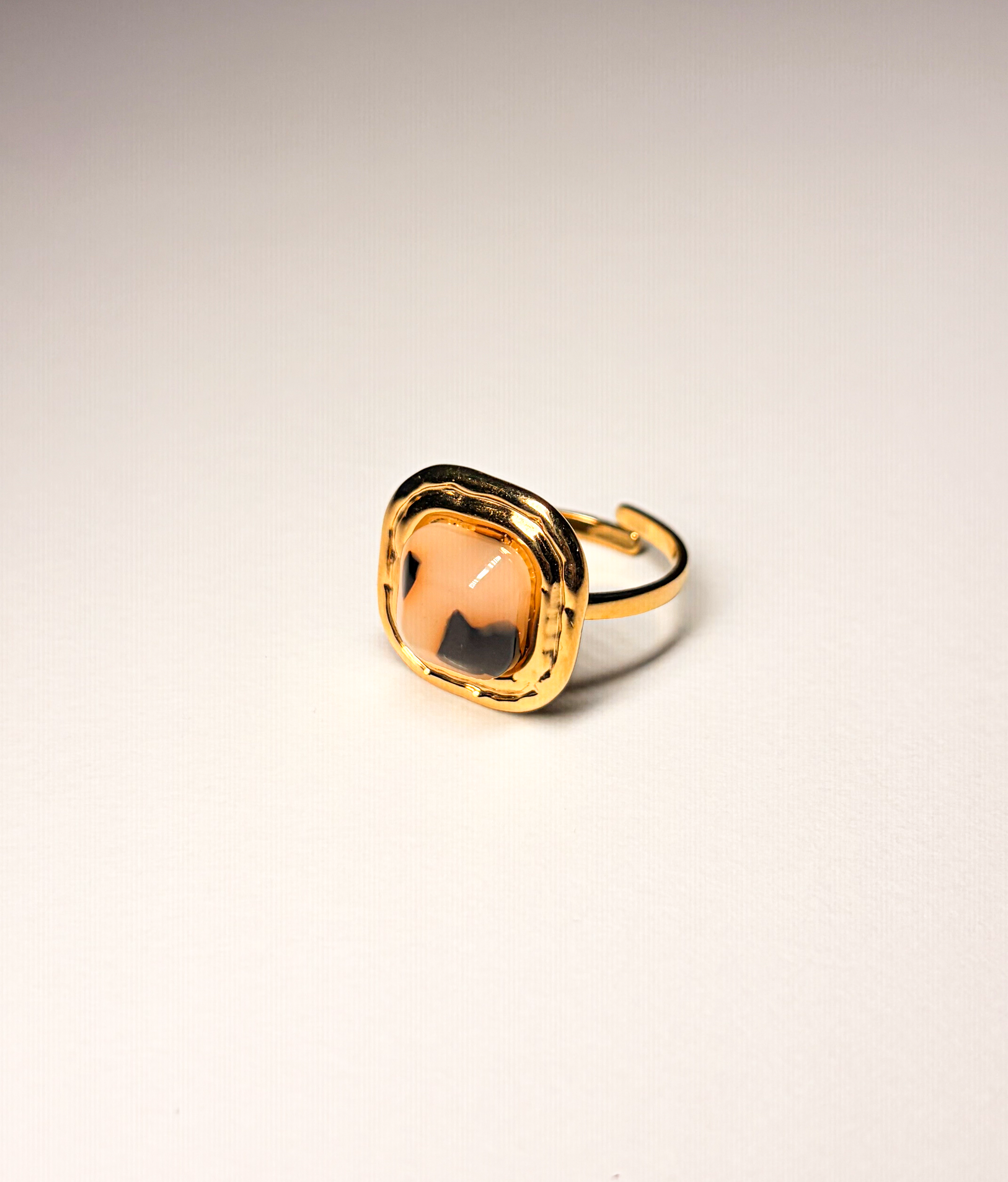 Bague ornementale avec une pierre rose et noire sur fond blanc.