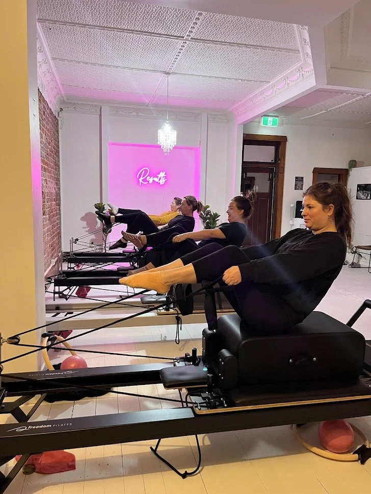 Four women exercising on Pilates reformer machines