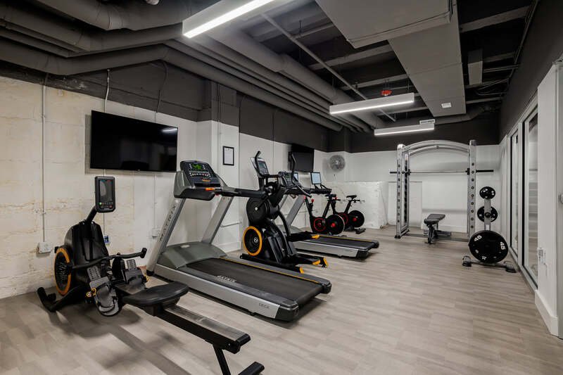 Interior of a modern gym with cardio machines, strength training equipment, and mirrors.