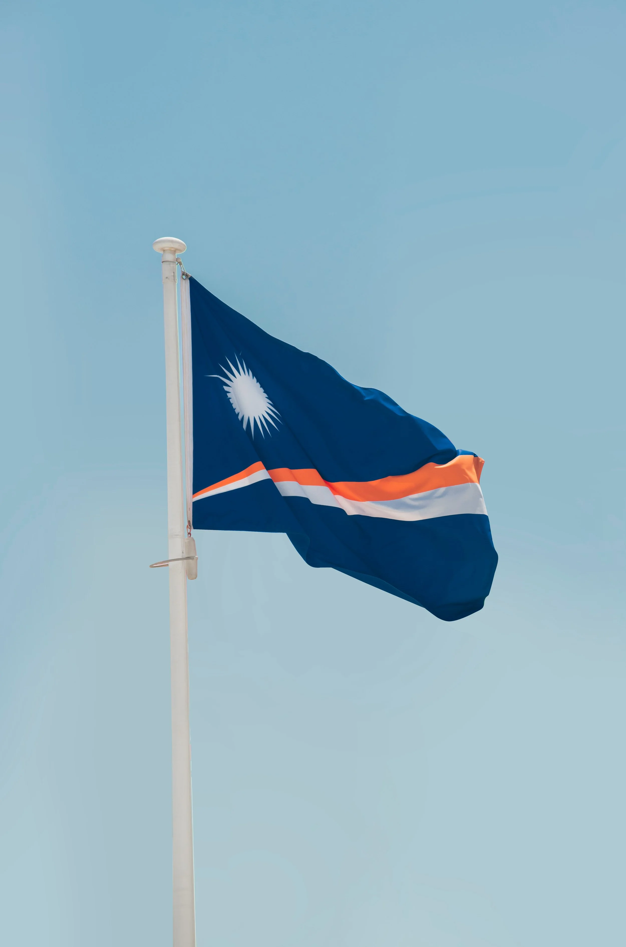 Flag of Namibia flying in the wind against a clear blue sky.
