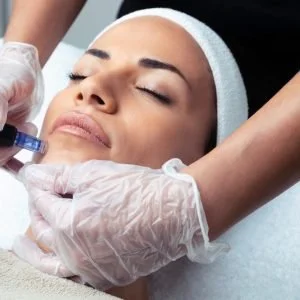 A woman receiving a facial treatment or injection from a medical professional wearing gloves.