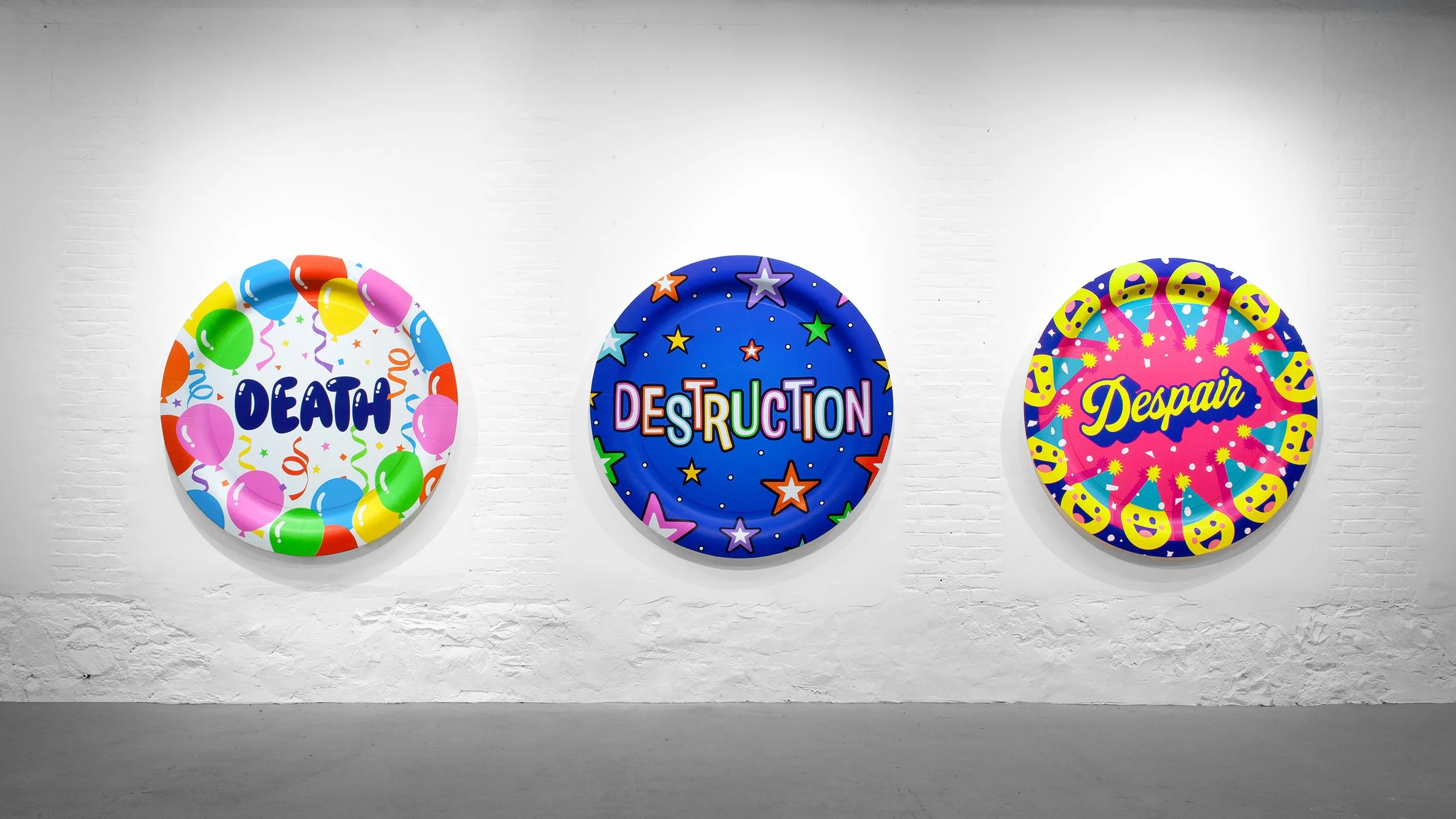 Three giant paper plates, displayed on a white wall. The first plate says 'DEATH' with balloon decorations, the second says 'DESTRUCTION' with stars and confetti, and the third says 'Despair' with smiley faces and celebration graphics.