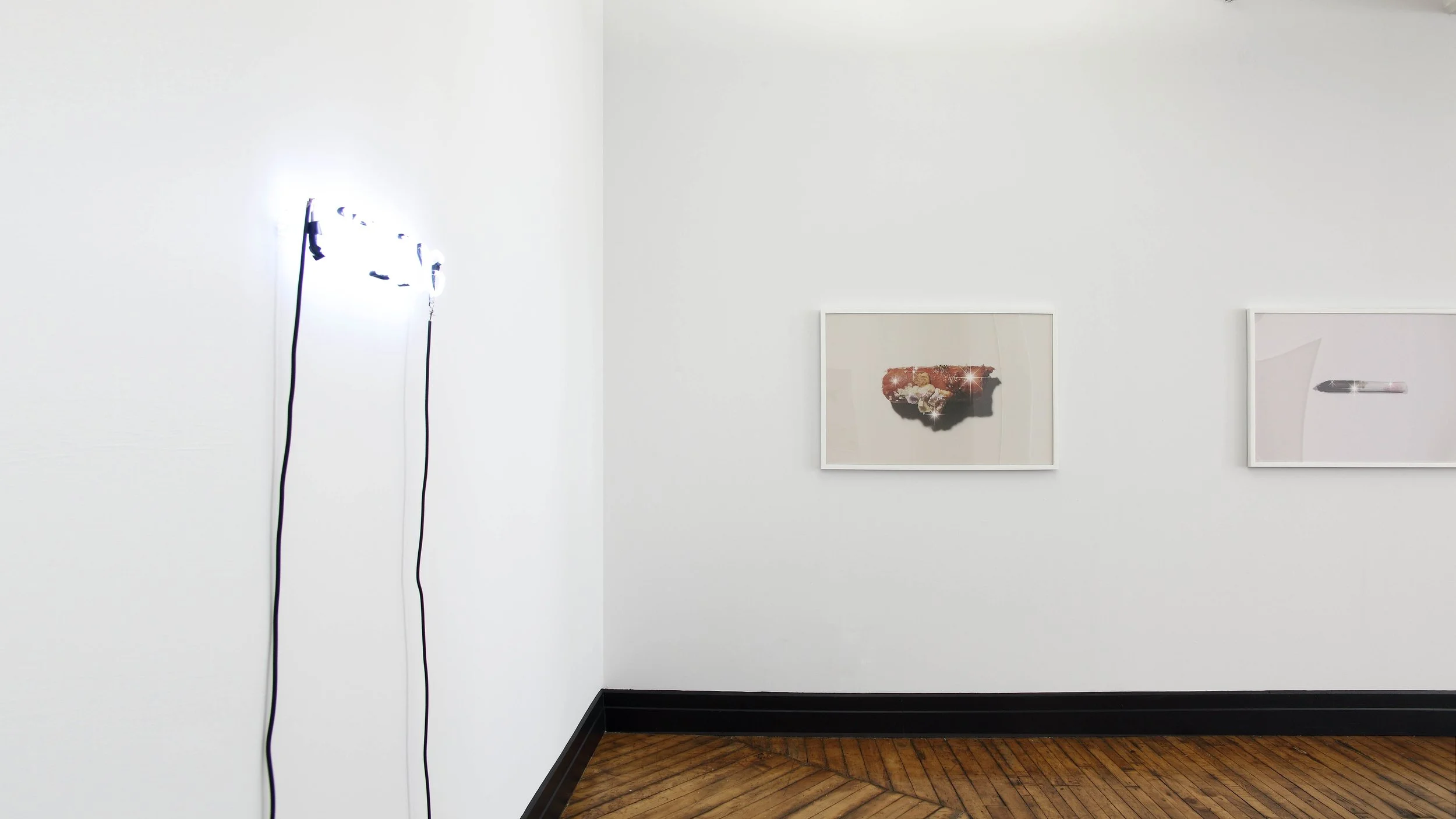 An art gallery installation of two framed photographs of garbage that sparkle like they are shiny and new. On the left is a neon sign that literally says 'NOTHING'.