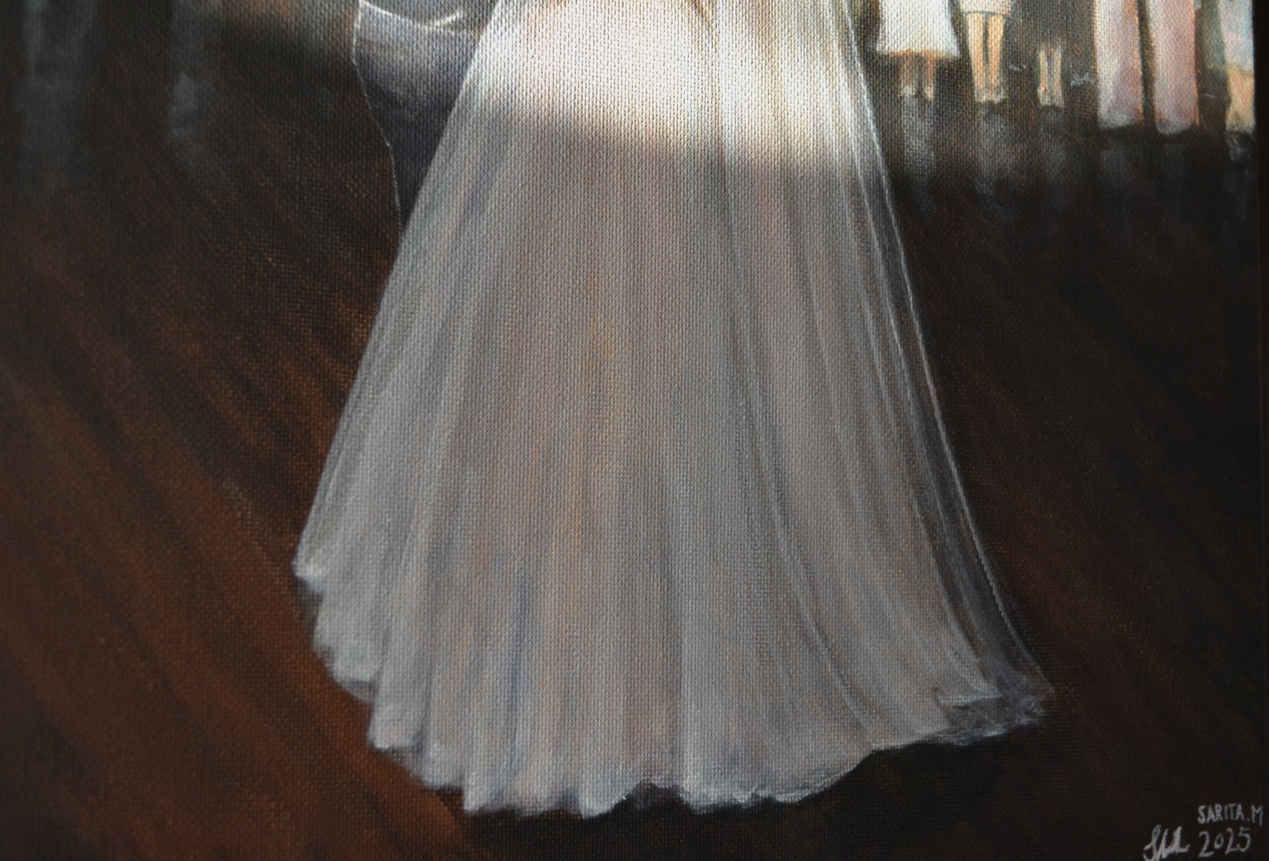 A white wedding dress on a hanger. The dress has a fitted bodice and a full, flowing skirt, displayed against a wooden floor with a dark background.