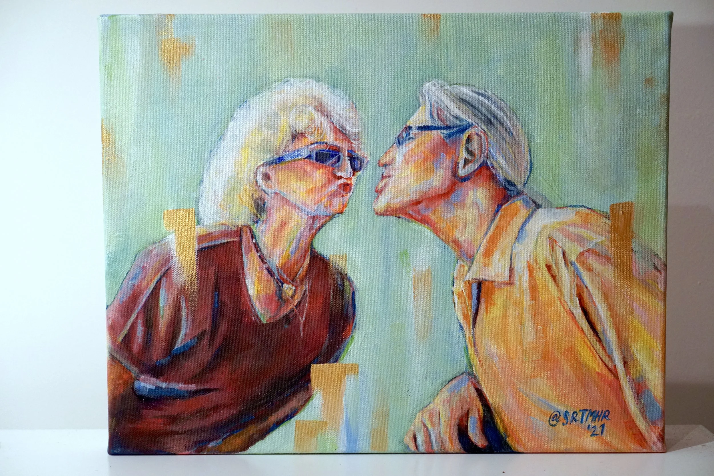 A colorful abstract painting of an elderly man and woman leaning toward each other, both wearing glasses and engaging in a close moment. The woman has short white hair and wears a dark red top, while the man has gray hair pulled back and wears a ligh