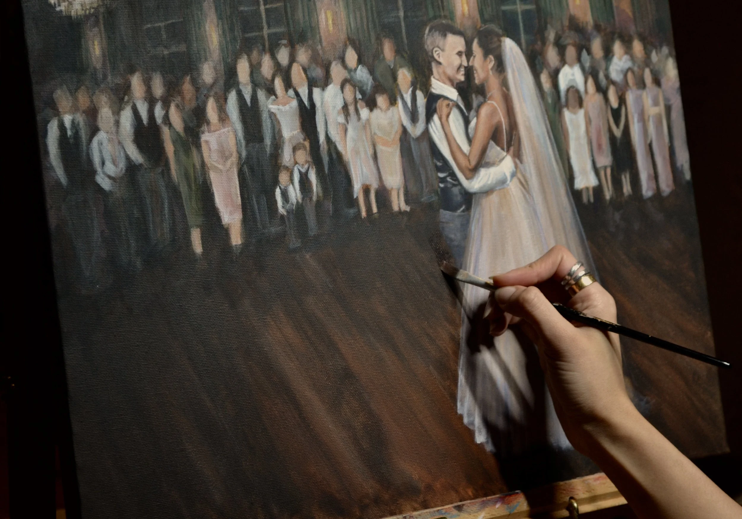 Artist painting a wedding scene on canvas, depicting a bride and groom dancing surrounded by wedding guests.