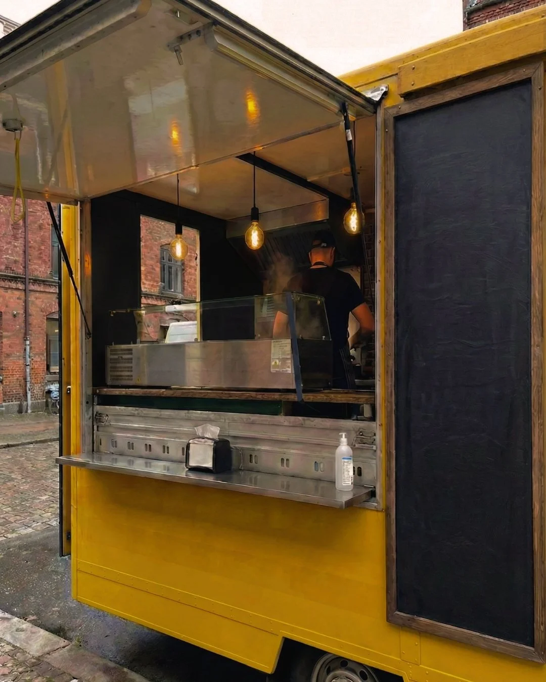 Gelber WeCaterIN Foodtruck mit geöffnetem Verkaufsfenster für Foodtruck-Catering in Berlin