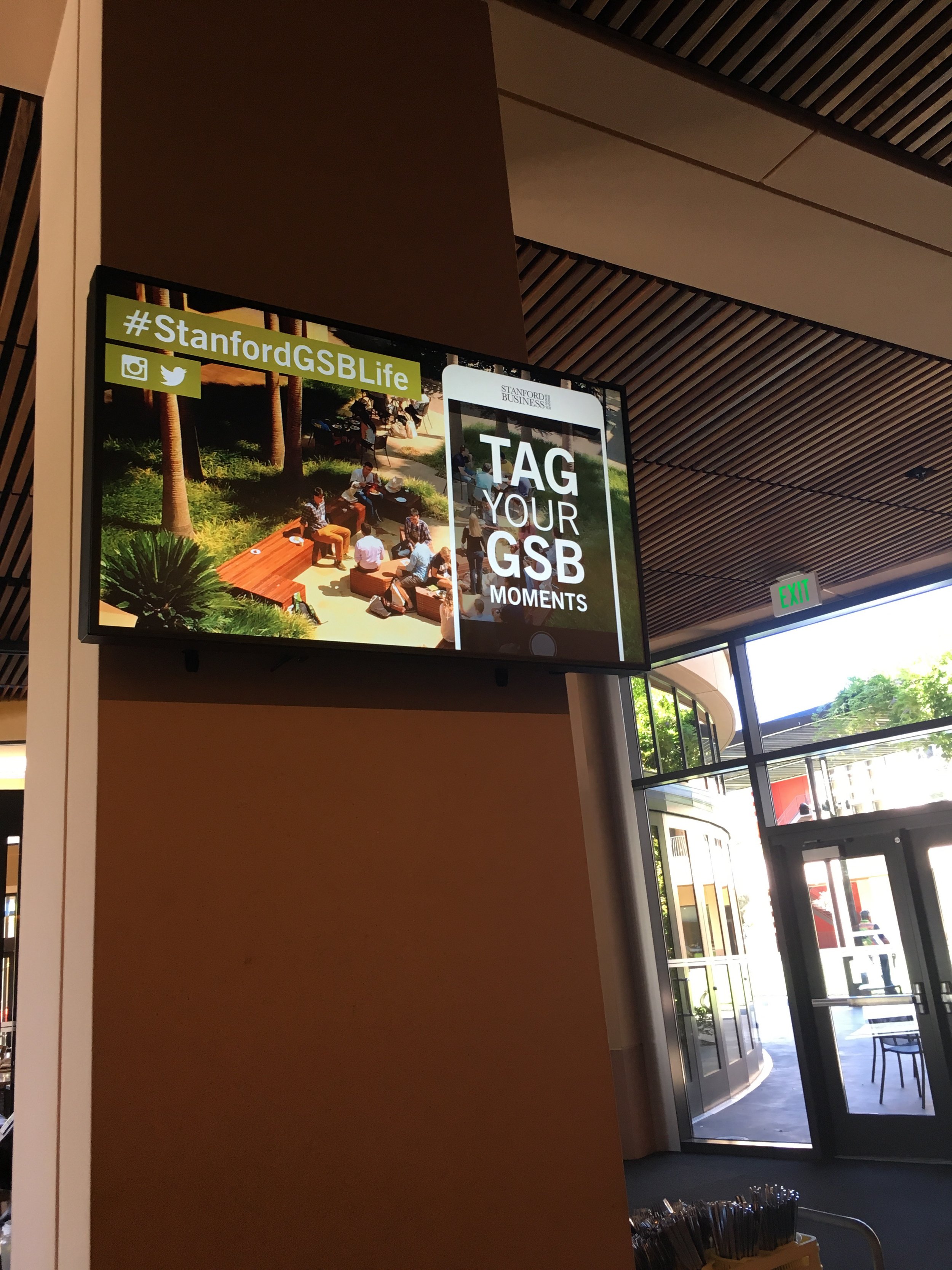 Digital screen displaying a hashtag promotional message for Stanford GSB Life, "Tag your GSB Moments" to engage staff, faculty, and students