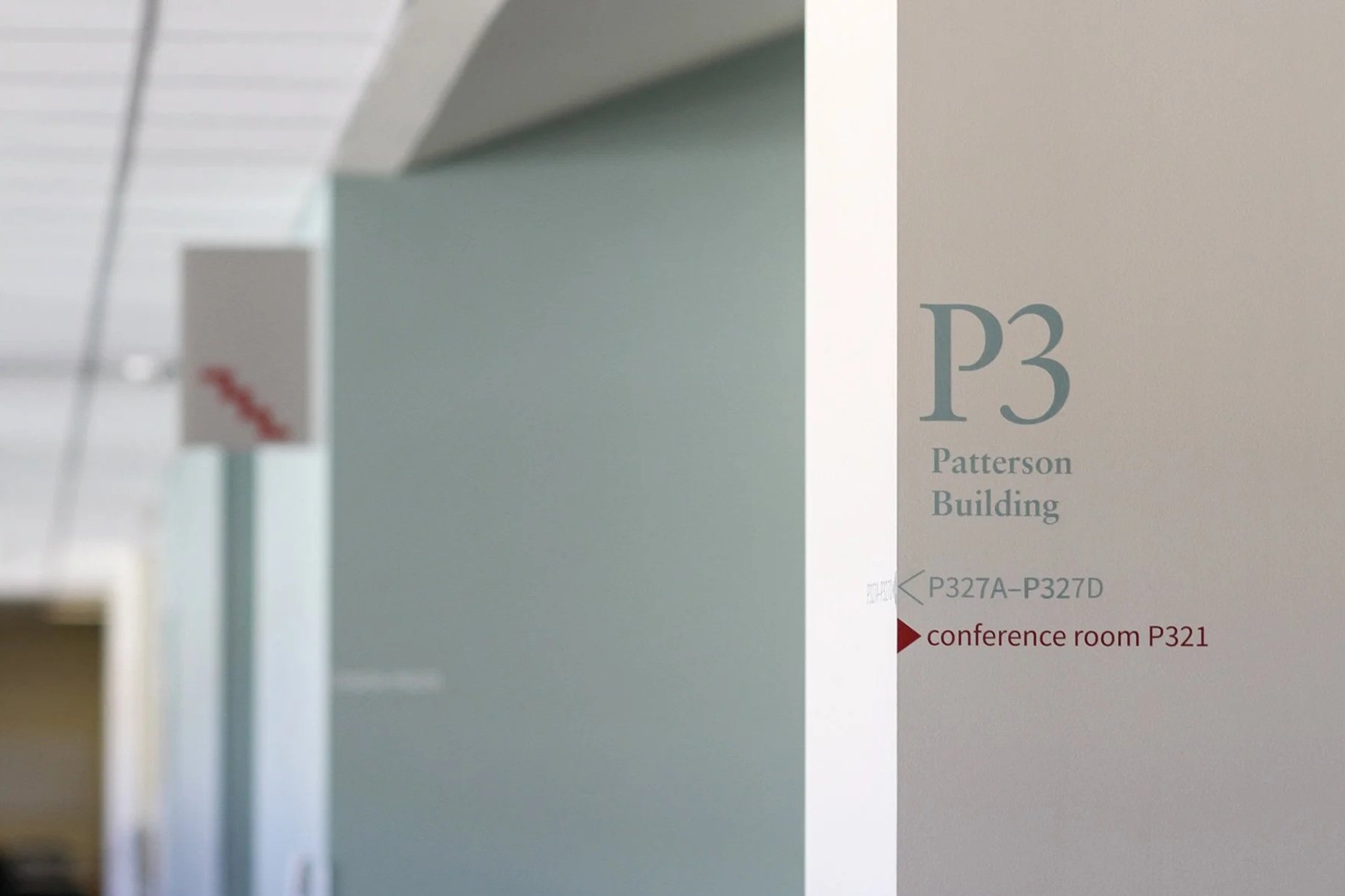 Wayfinding at Stanford Graduate School of Business: Wall decals indicating P3 Patterson Building, with additional signs for conference room P321 and other rooms P327A to P327D in a hallway.