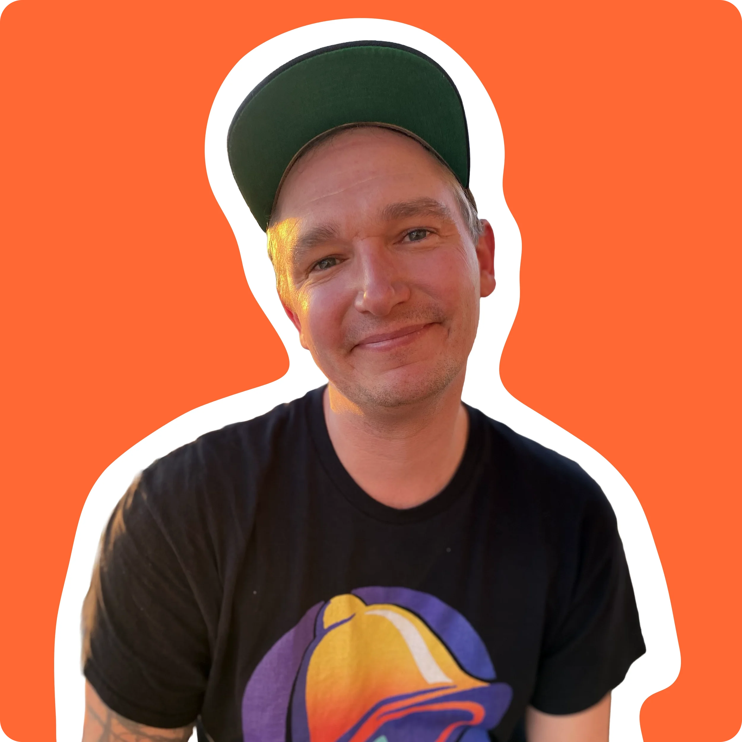 Sound and music producer wearing green hat and black T-shirt, smiling, portrait against a bright orange-ish background.