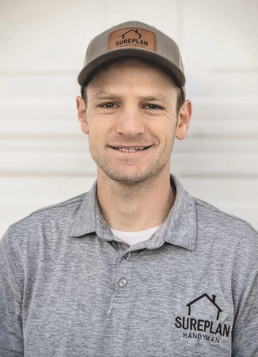 Mike wearing a gray polo shirt with 'SUREPLAN HANDYMAN' logo and a gray cap with the same logo, standing in front of a white background.