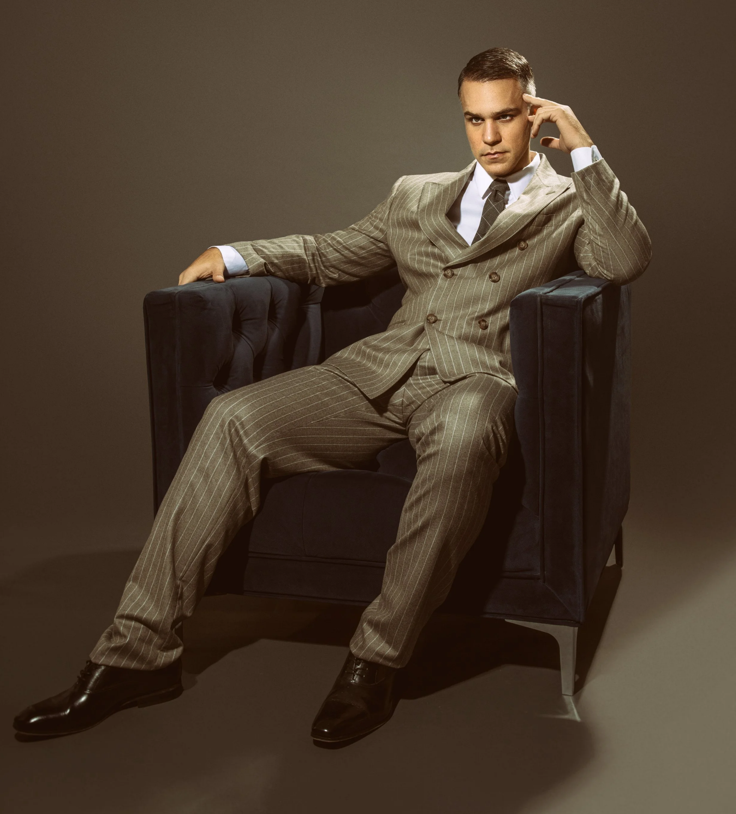American-Greek-EU actor Taso Mikroulis Sag/aea actor in a suit in a chair,, grey mixed brunette 40s male