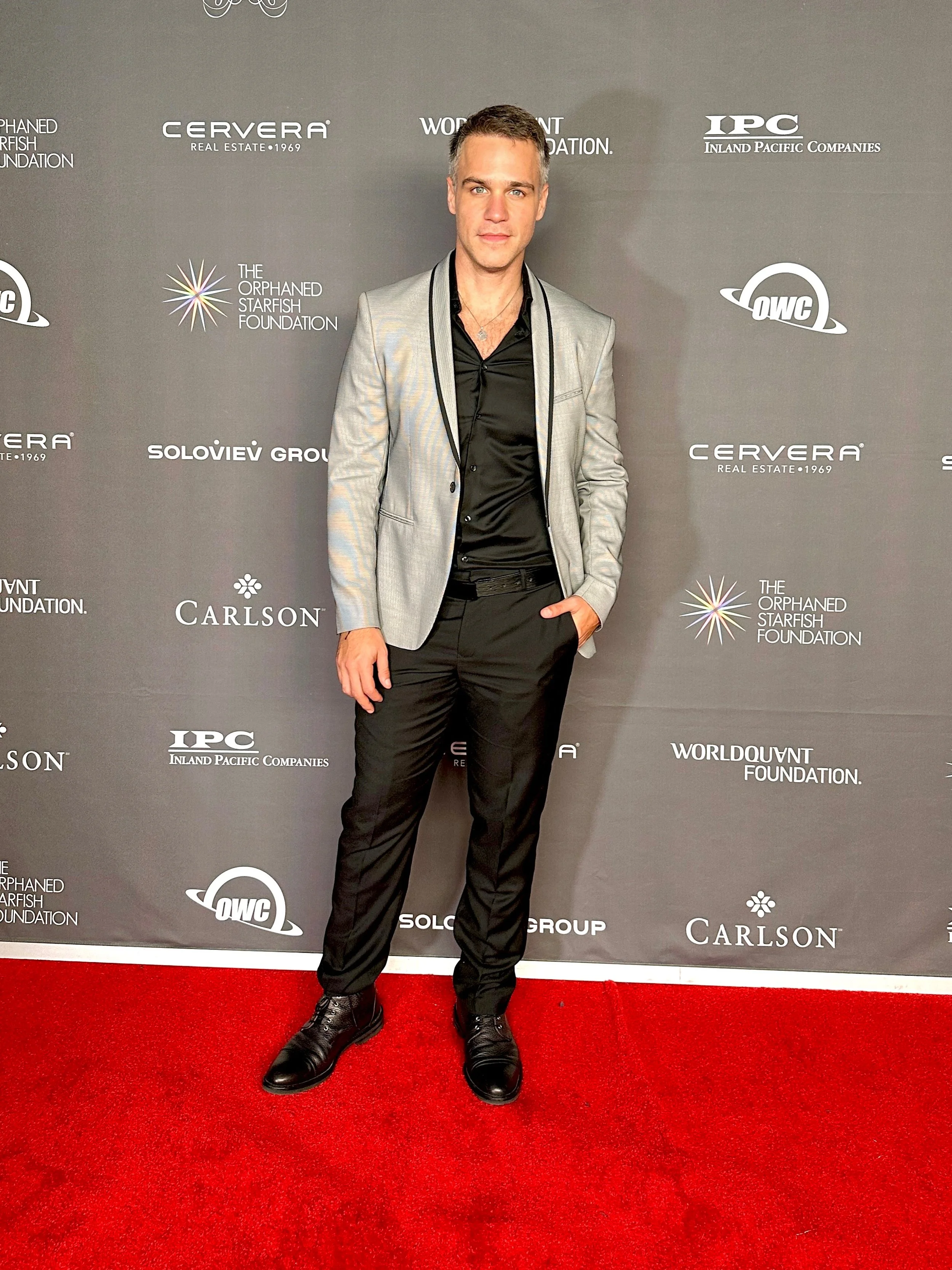 American-Greek-EU actor Taso Mikroulis Sag/aea actor in a suit on the red carpet of Orphaned Starfish gala, hazel eyes, grey mixed brunette 40s male