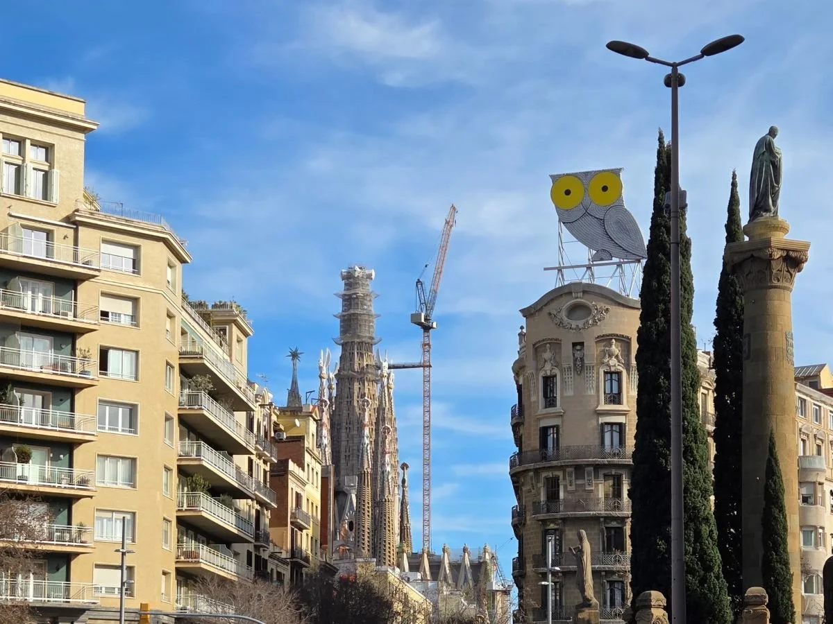 Udsigt til La Sagrada Familias tårne og det genkendelige ugle-skilt - Buho de Barcelona, taget fra Plaça de Jacint Verdaguer.