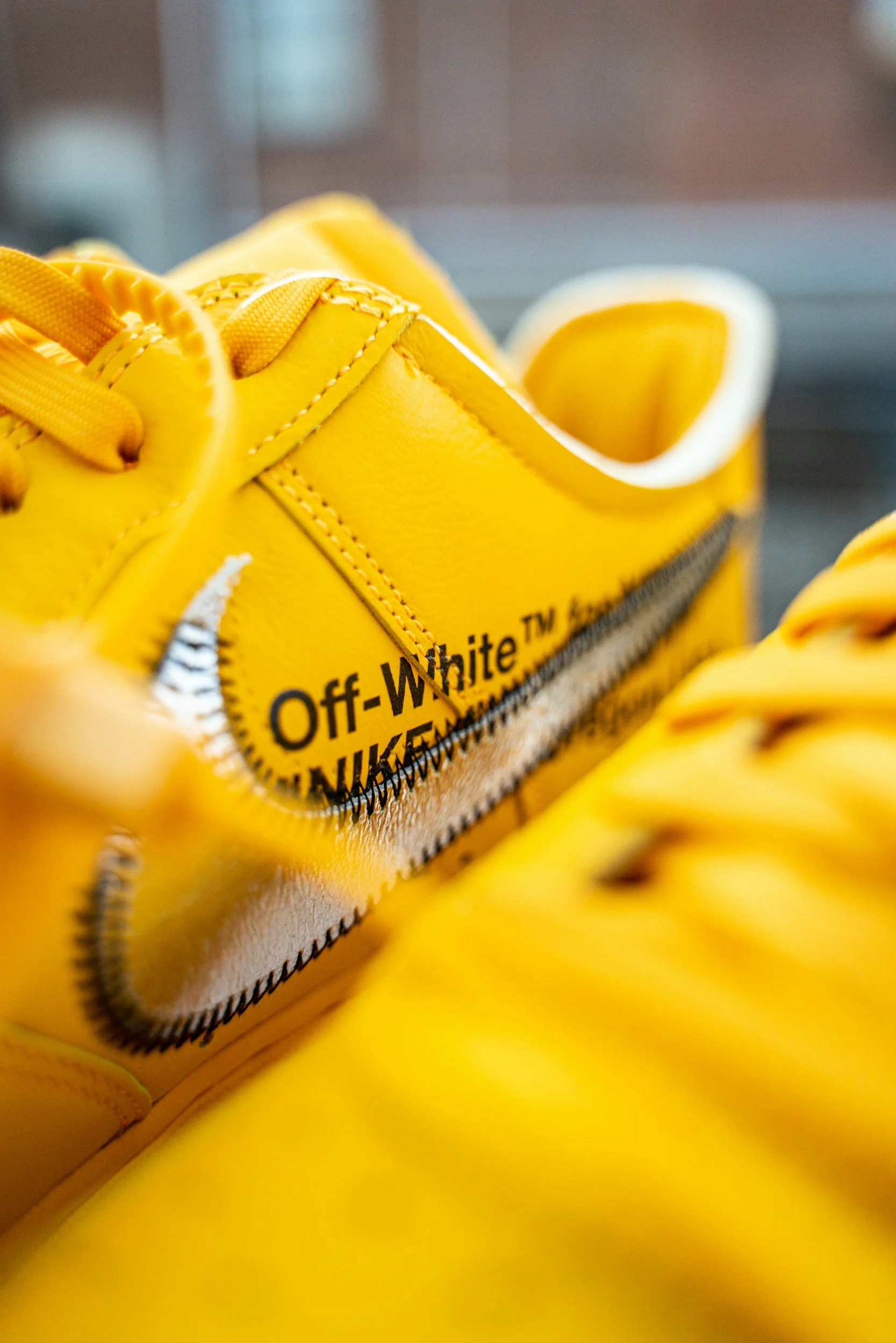Close-up of a yellow Off-White x Nike sneaker with black text on the side and yellow laces.