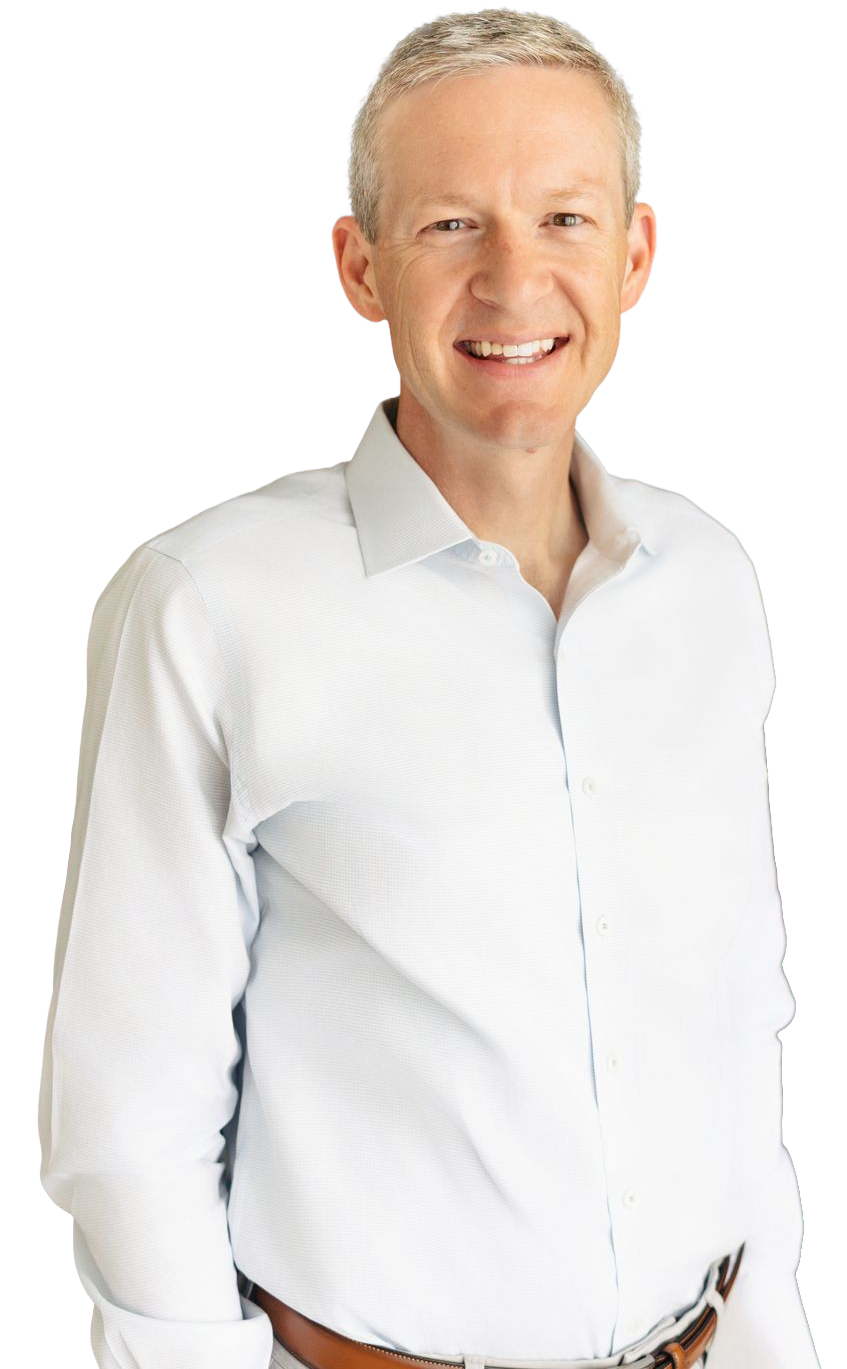 Smiling man with short gray hair wearing a white button-up shirt, posing against a black background.