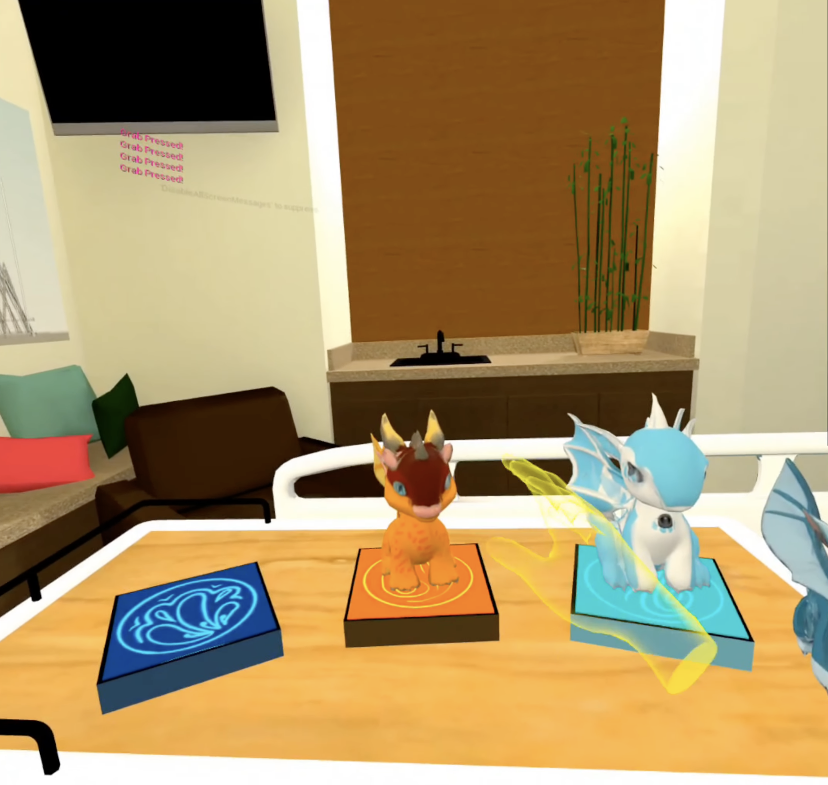 Virtual room with three digital characters on a table, including a small dragon, a fox-like creature, and a fish with wings, each on a colorful platform.
