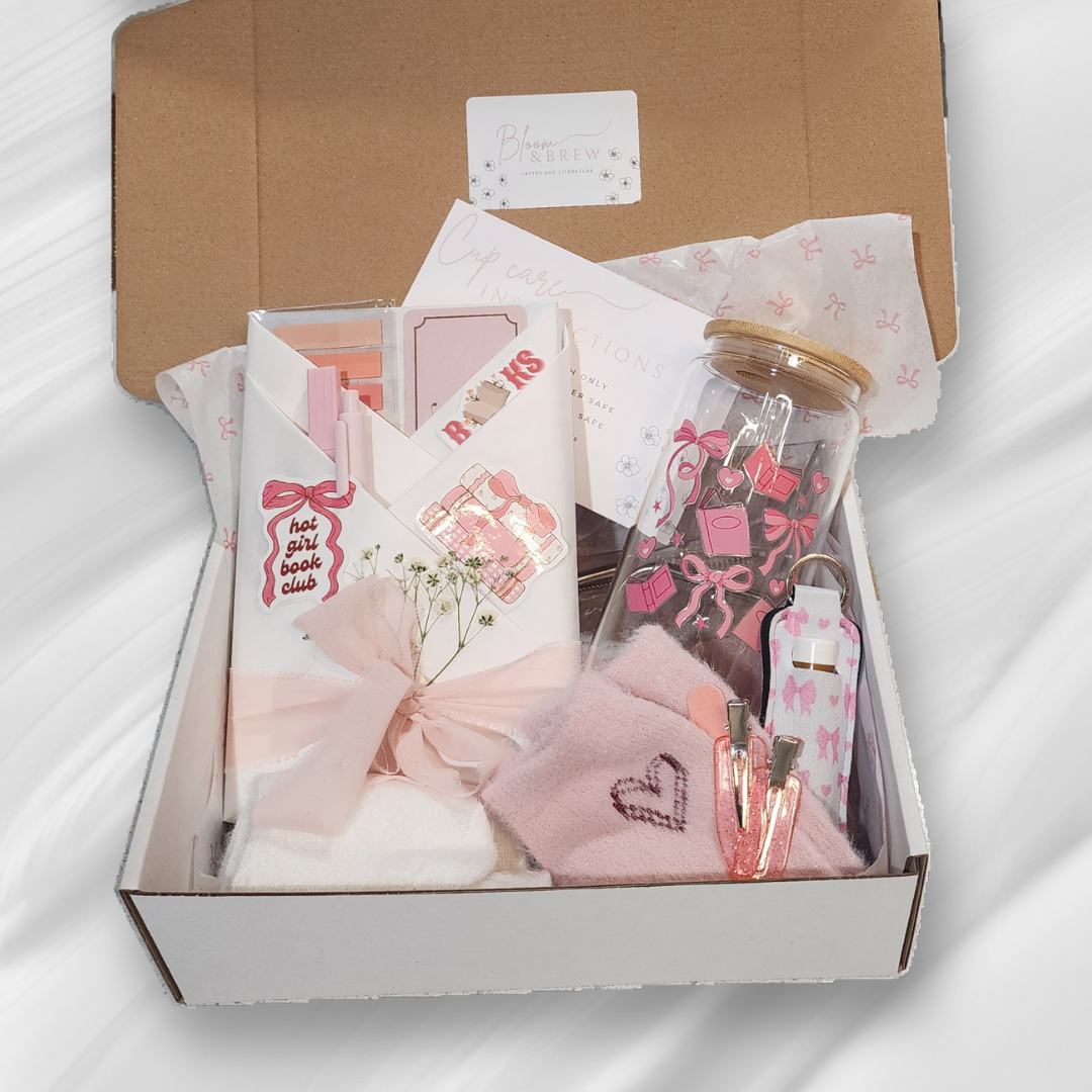 Pink and white gift box filled with stationery, accessories, and small decorative items, including a jar with pink stickers, clip, hair tie, and notes.
