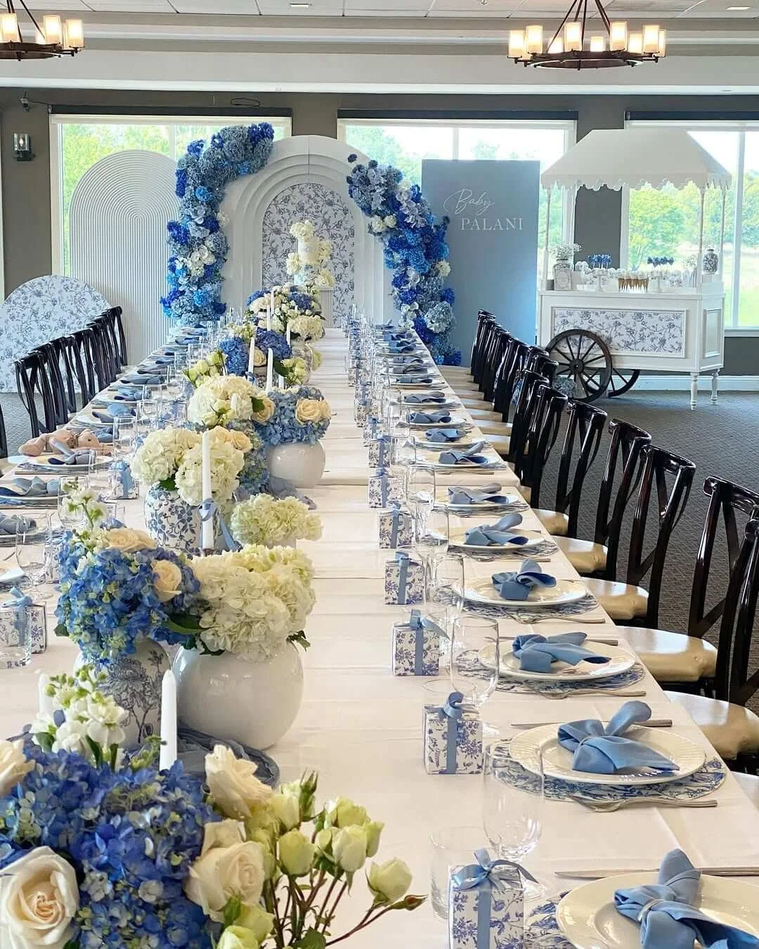 Blue and white baby shower event design with floral table setup and arched backdrop in Texas