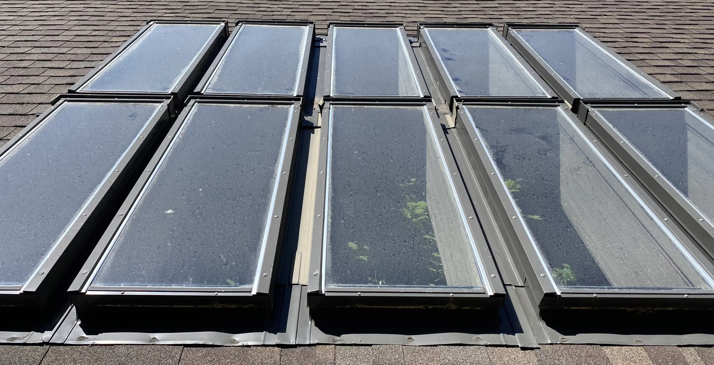 A metal roof with multiple skylights installed in a row.