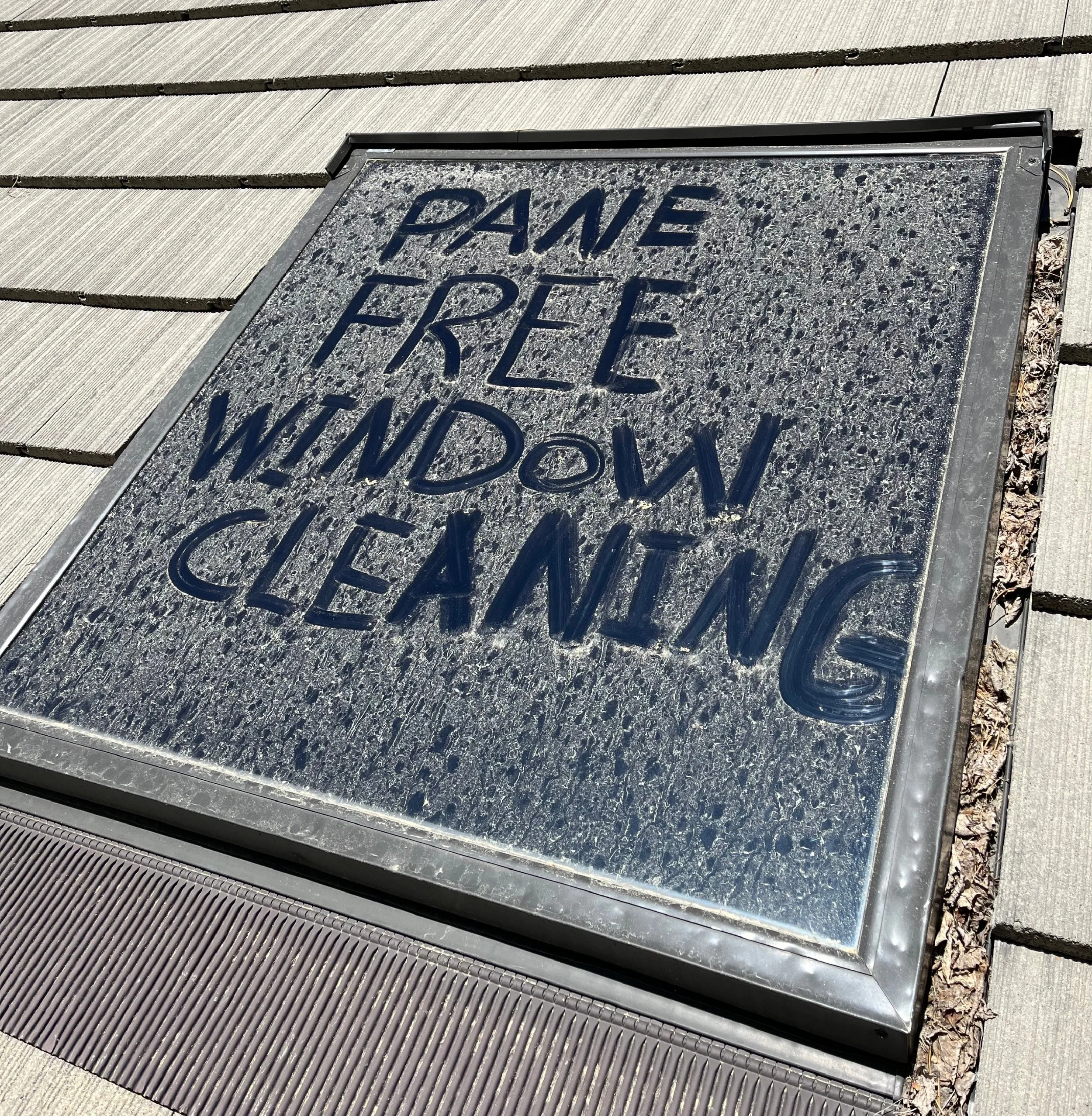 Windows covered in dirt with the words "PANE FREE WINDOW CLEANING" written on it highlighting the need for having the windows cleaned.