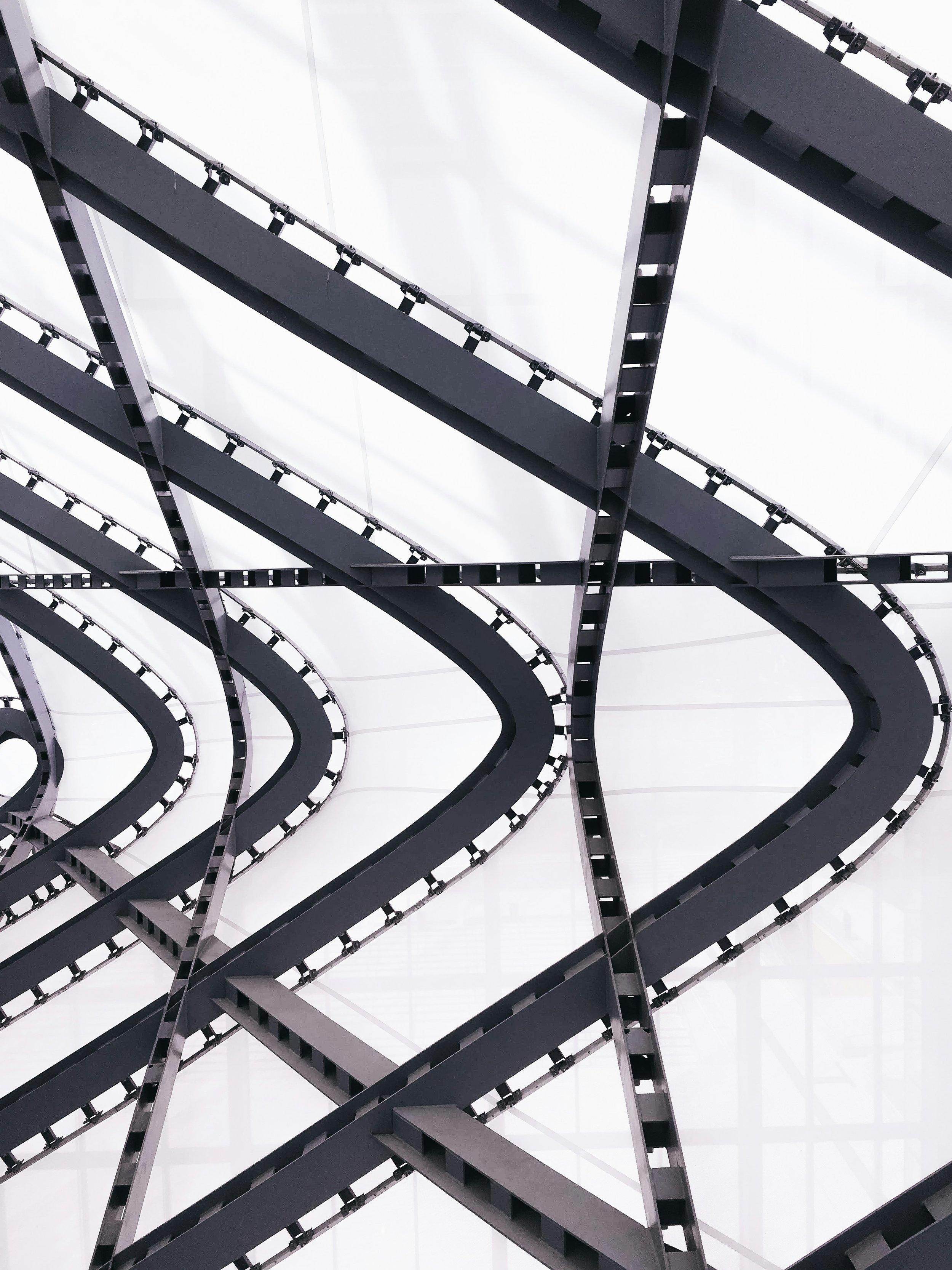 A modern, abstract architectural interior with black metal curved escalators or walkways against a white ceiling.