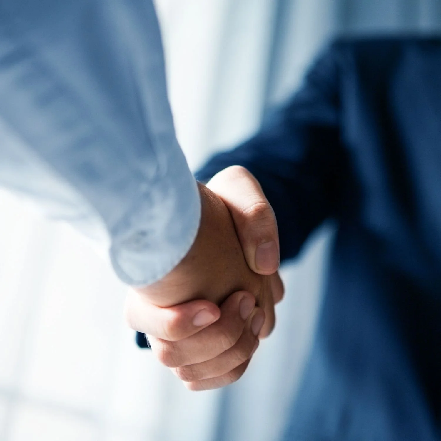 Two people in business attire shaking hands in a professional setting.