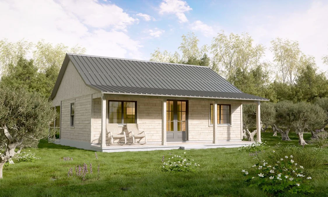 A small, wooden house with a metal roof, front porch with two chairs, surrounded by green grass and trees.
