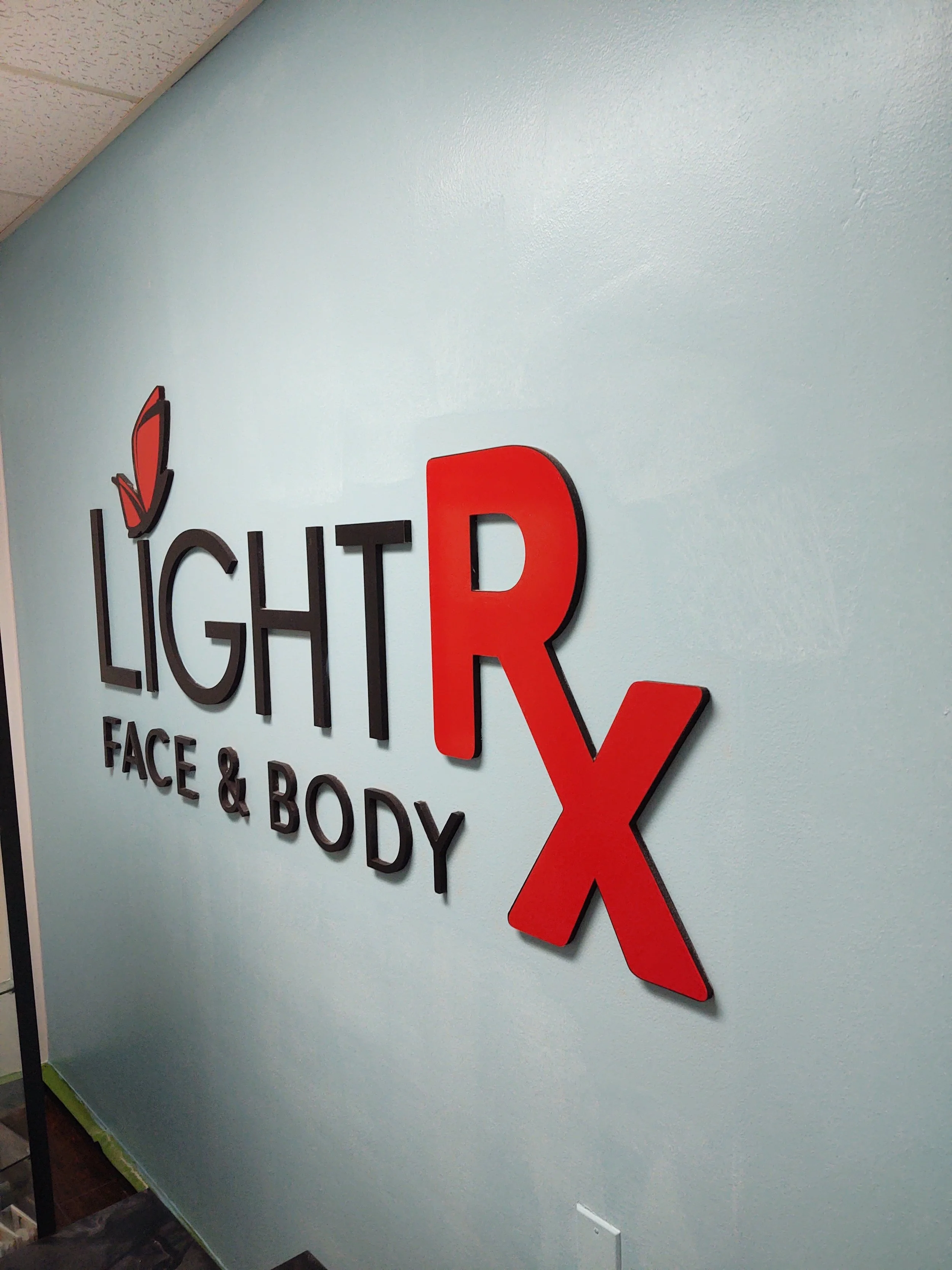 Interior wall with a sign that says "LightRx Face & Body" and features a red butterfly logo.