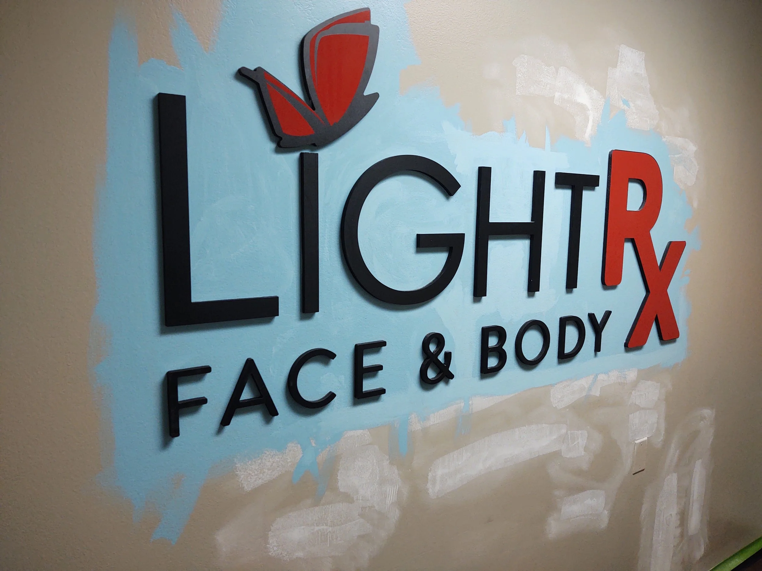 Sign with the text "LightRx Face & Body" featuring a red and black butterfly logo at the top left.
