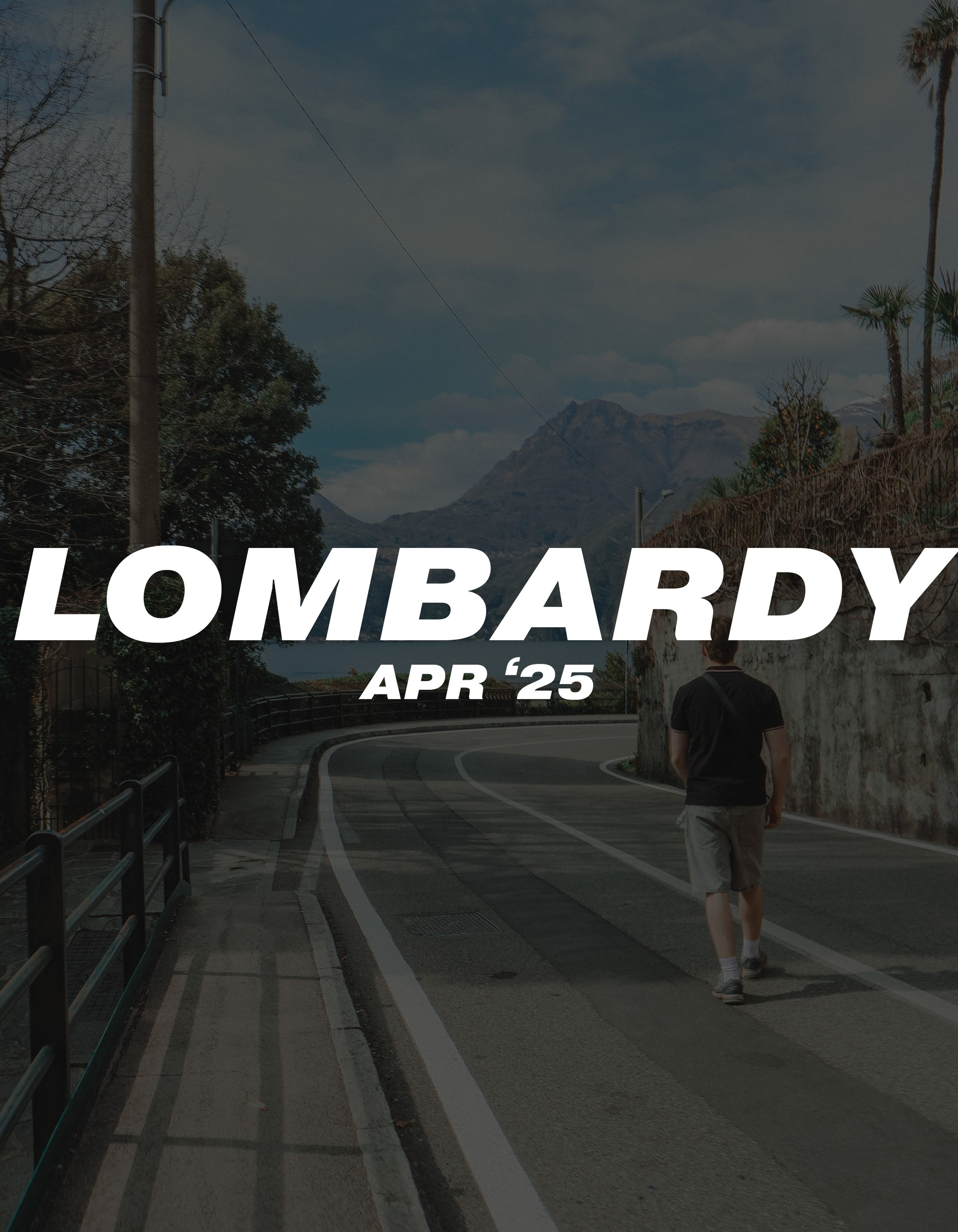 A person walking along a winding mountain road with a scenic background of mountains, trees, and a partly cloudy sky.