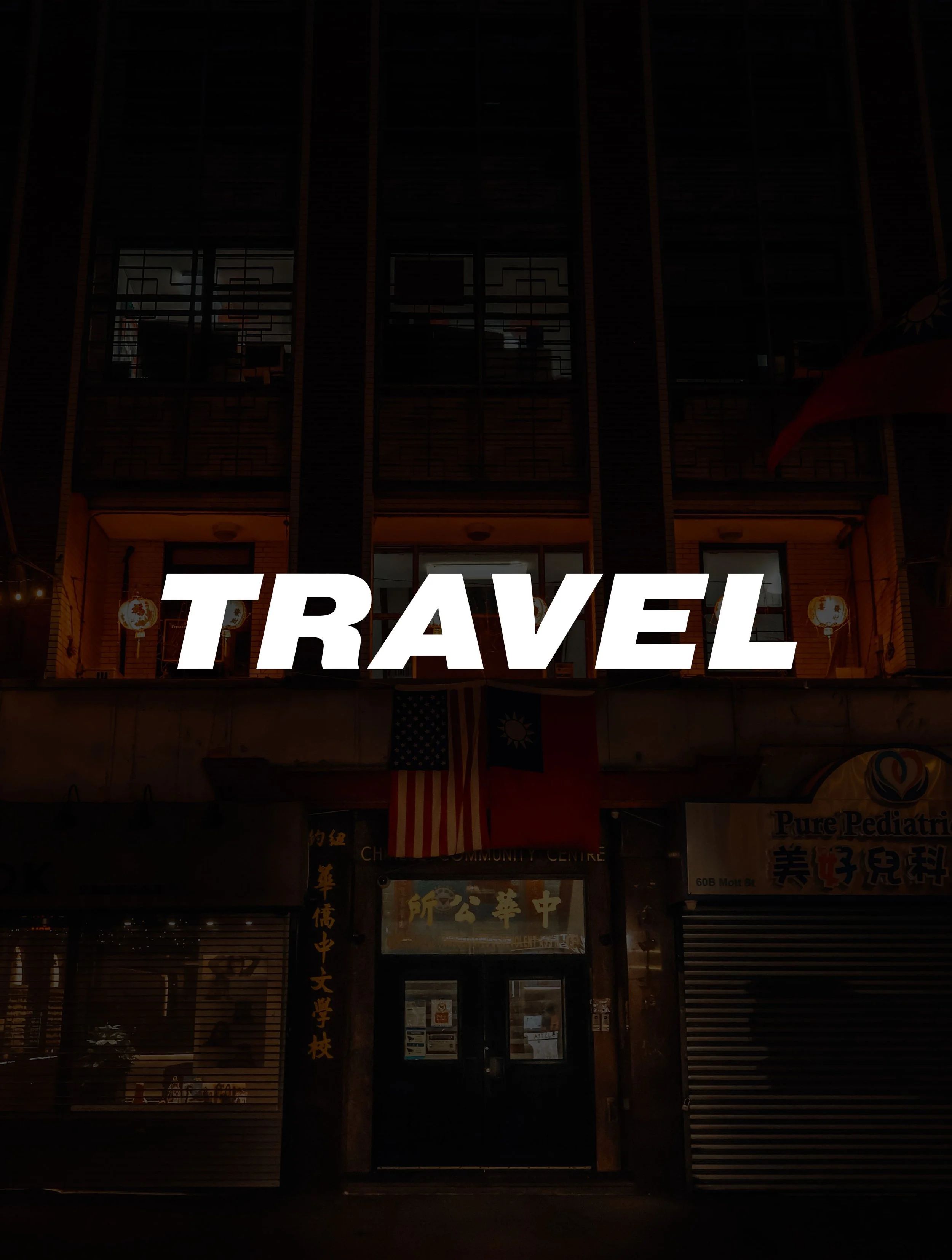 Nighttime photo of a building with illuminated signs and flags, with the word 'TRAVEL' in bold white letters across the center.