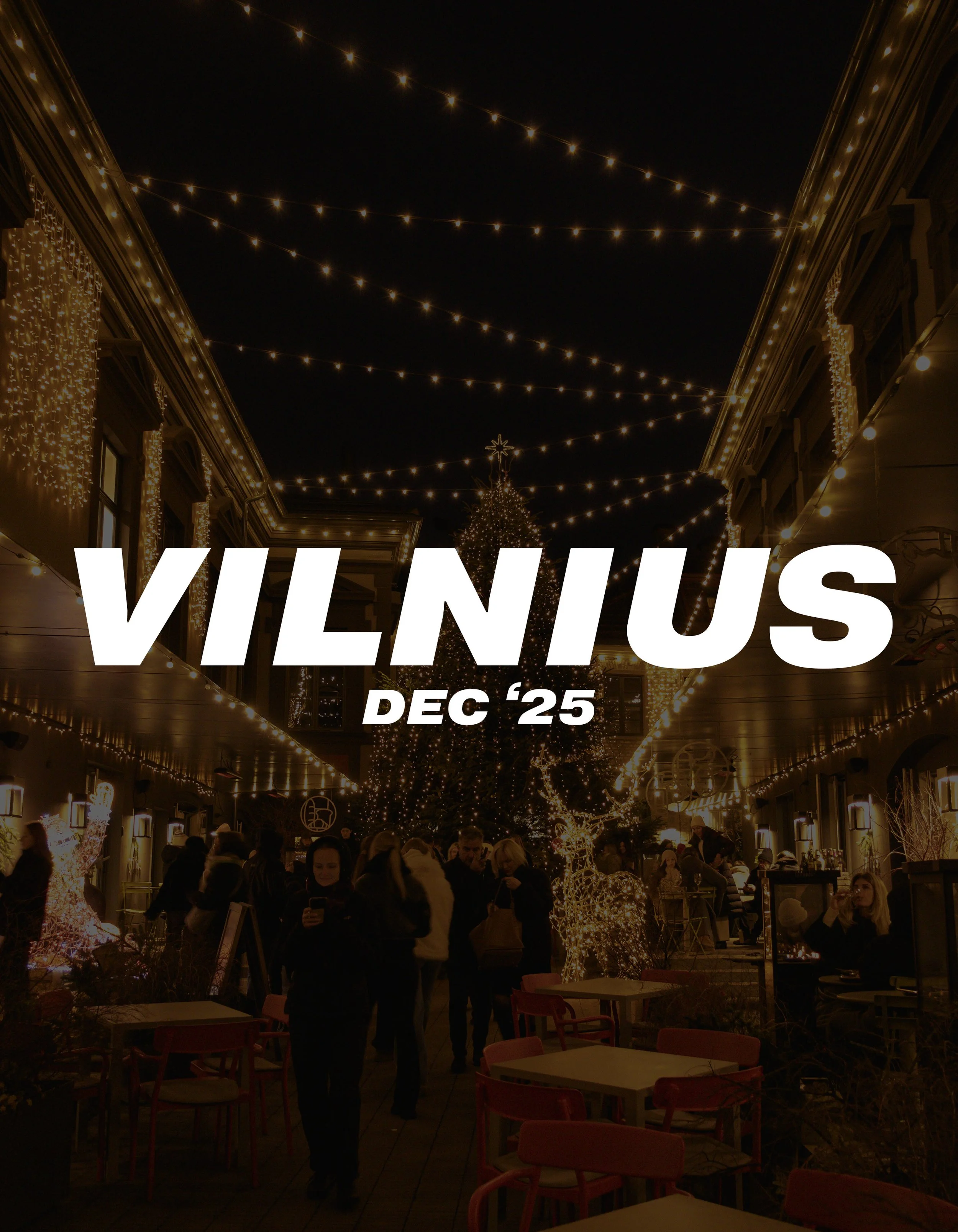 People dining outdoors at night with Christmas lights and a decorated Christmas tree in Vilnius, December 2025.