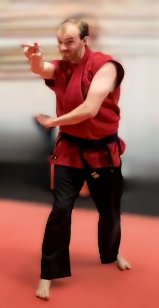 A man dressed in a martial arts uniform performing a martial arts move in a pose.