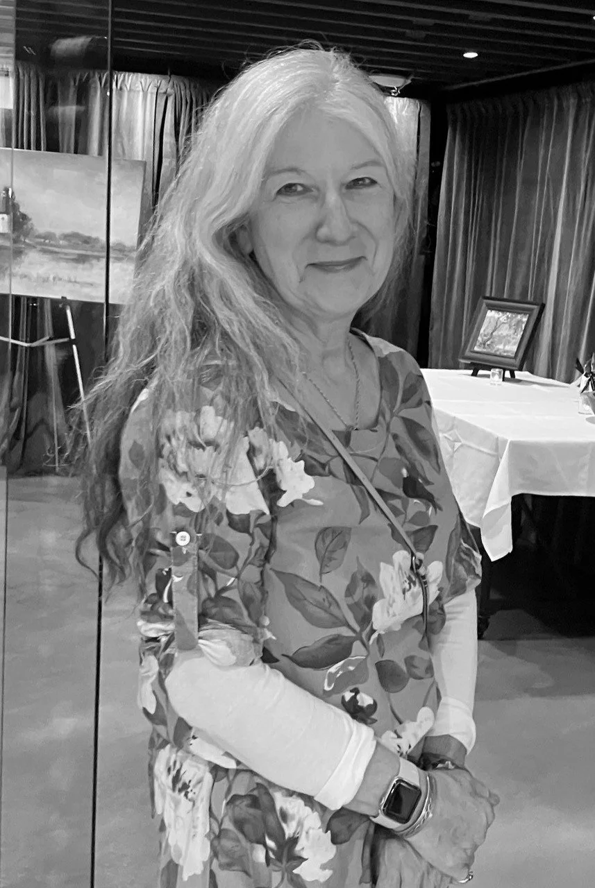 An older woman wearing a wide-brimmed hat holds a fluffy dog close to her face outdoors.