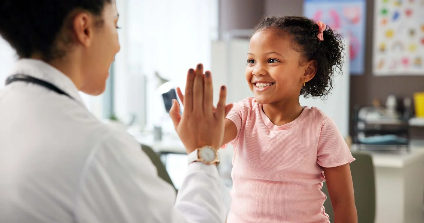 child in pink shirt giving a high five during speech therapy