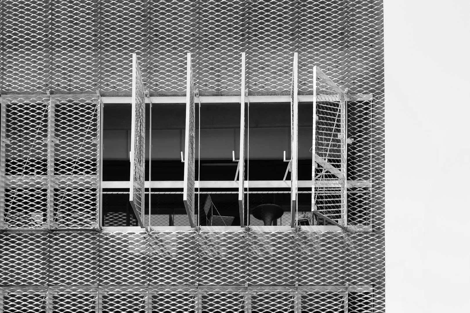 Ventanas abiertas en un edificio de estructura metálica con revestimiento de malla metalica desplegada.