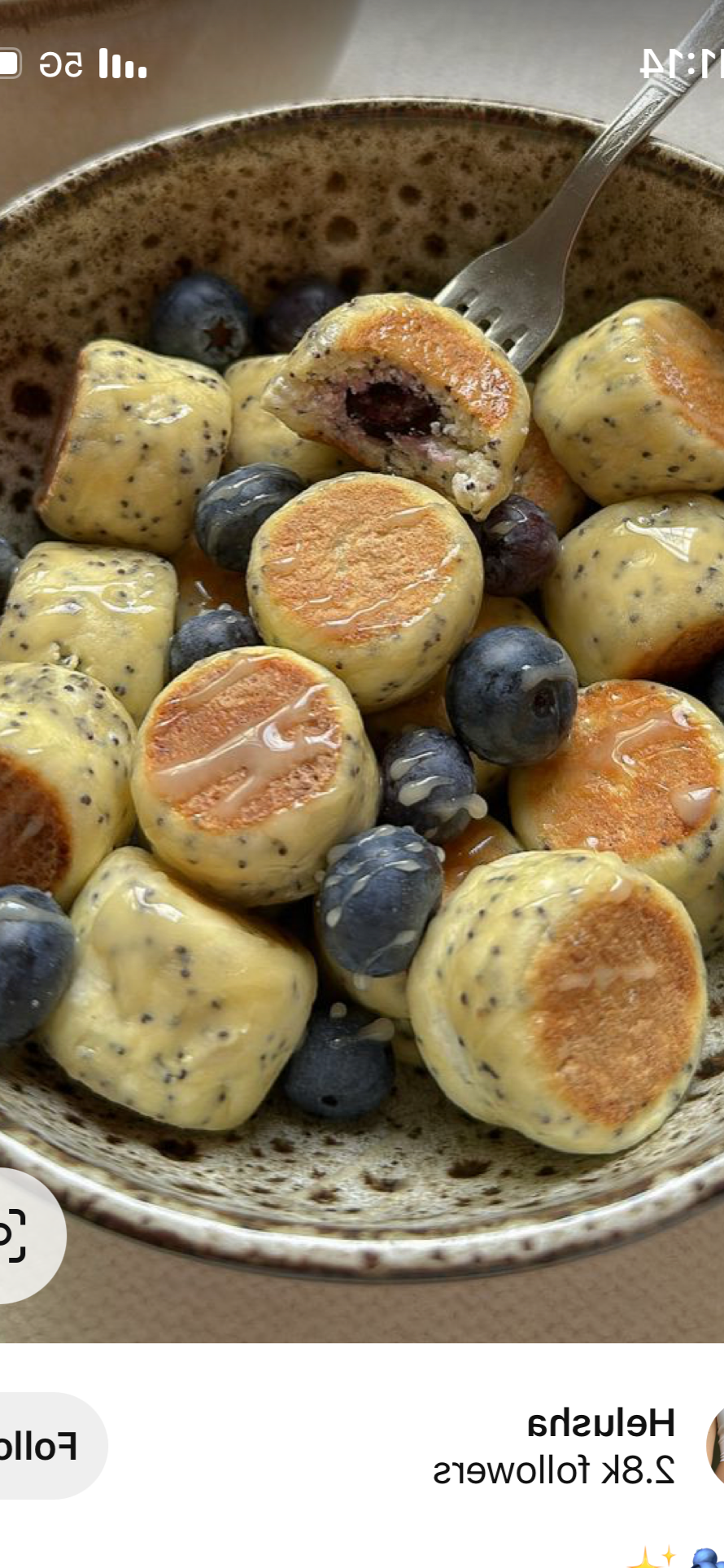 Creamy blueberries stuffed with a filling, topped with a drizzle of honey or syrup, served with fresh blueberries in a speckled ceramic bowl.