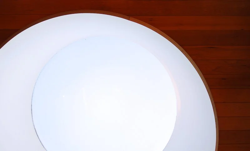 Close-up of a circular light fixture on a wooden ceiling. brahlerdesign.