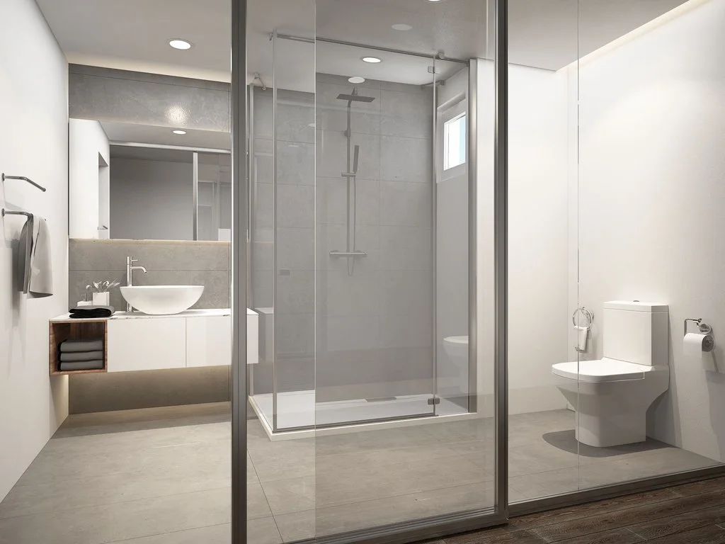 Modern bathroom with a glass-enclosed shower, white toilet, and a white vanity with a round vessel sink by brahlerdesign.