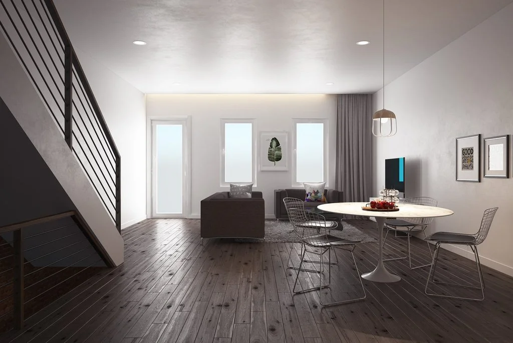 Modern living room with wooden floors, a staircase on the left, a sofa and two chairs near two windows, a wall-mounted TV, and a round dining table with chairs on the right by brahlerdesign.