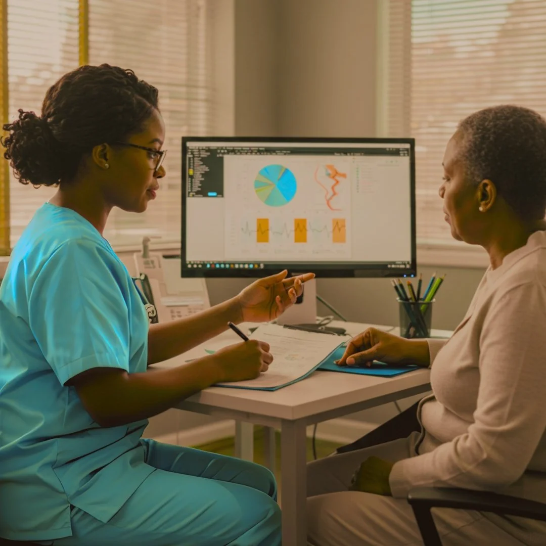 Two women in a medical office having a discussion while looking at a computer screen displaying charts and graphs.