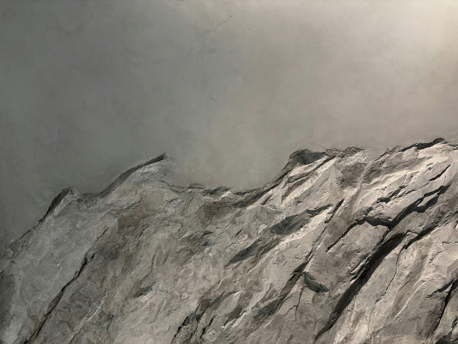 Close-up of a textured gray stone or concrete wall with a rough, jagged surface.