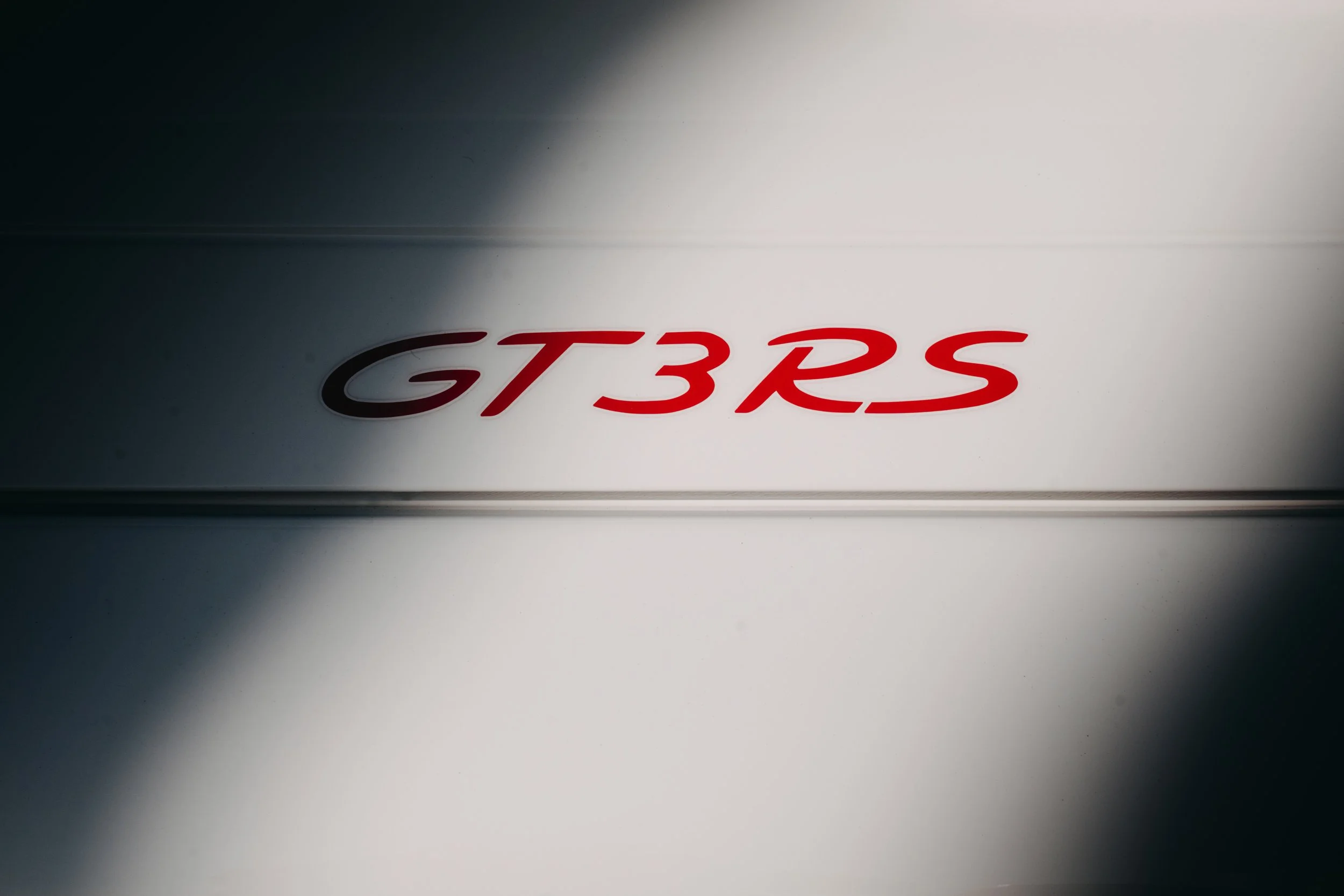 Close-up of a white surface with a red and black 'GT3RS' emblem