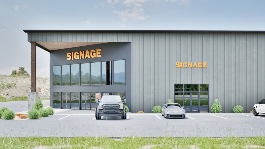 Modern commercial building with large signage, glass entrances, and parked cars in front, surrounded by landscaped bushes and grass.