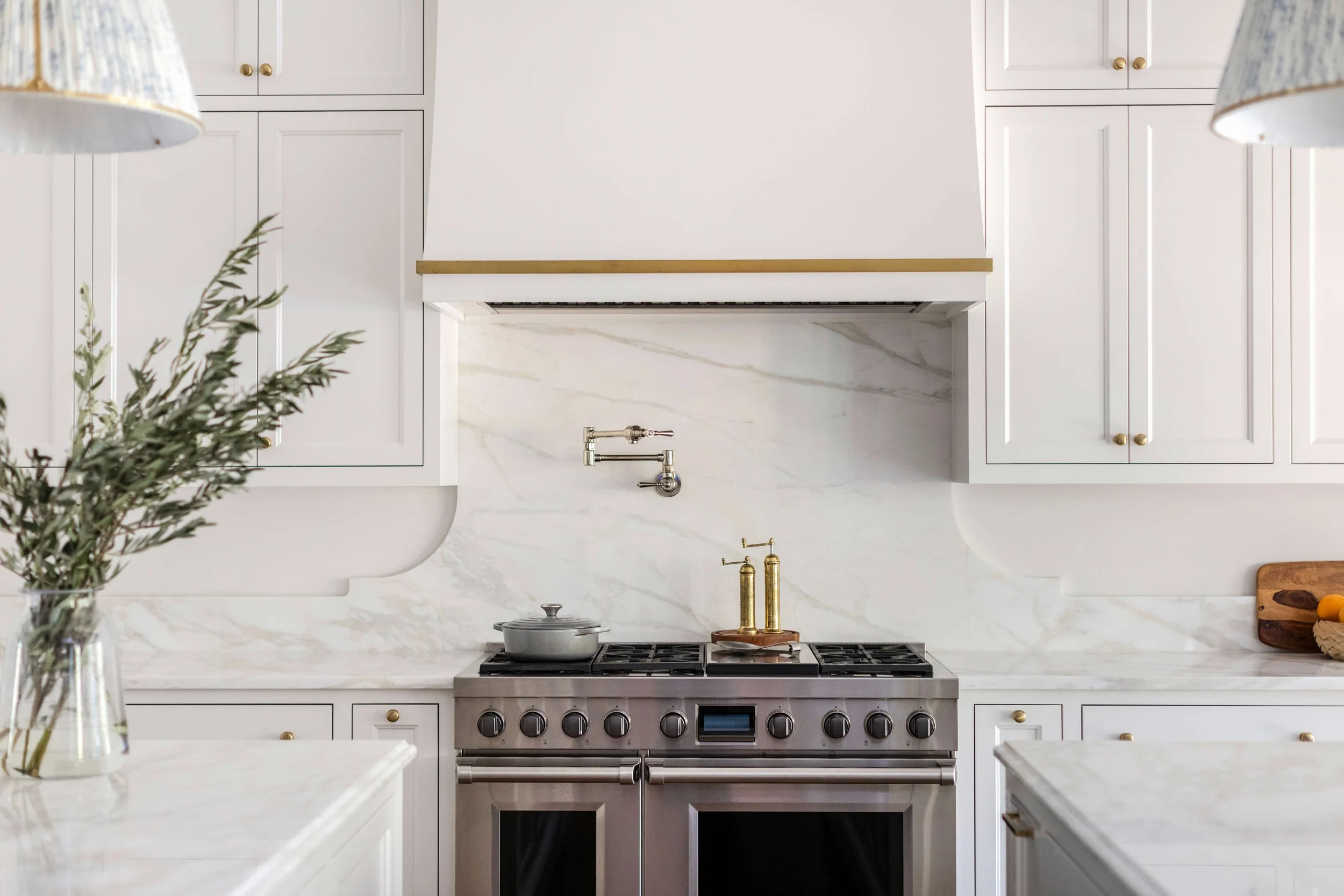 Kitchen with white cabinets, marble backsplash, and stainless steel stove with black control knobs