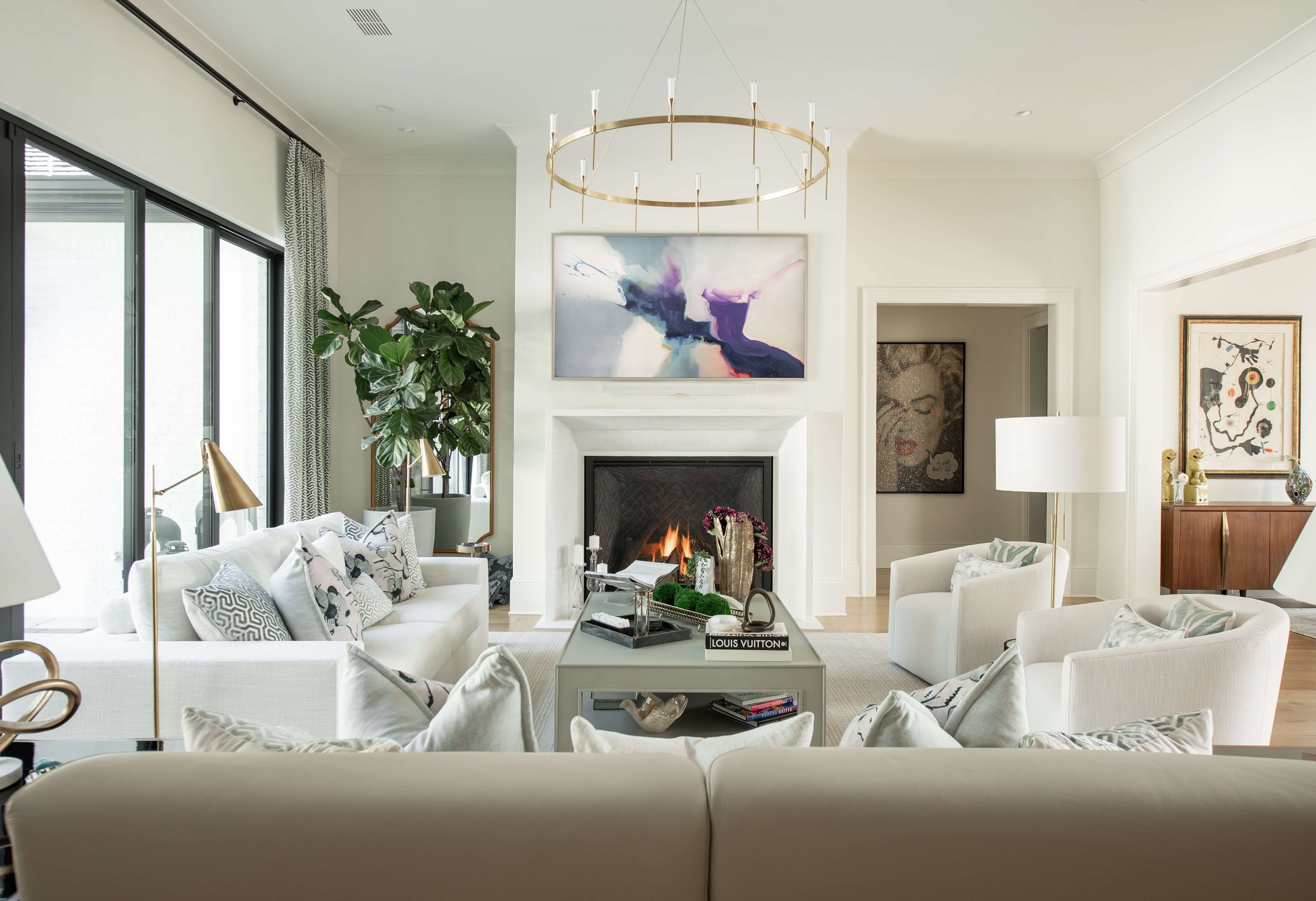 Modern kitchen with white marble island, pendant lights, a large vase with greenery, and a built-in bar area with liquor bottles.
