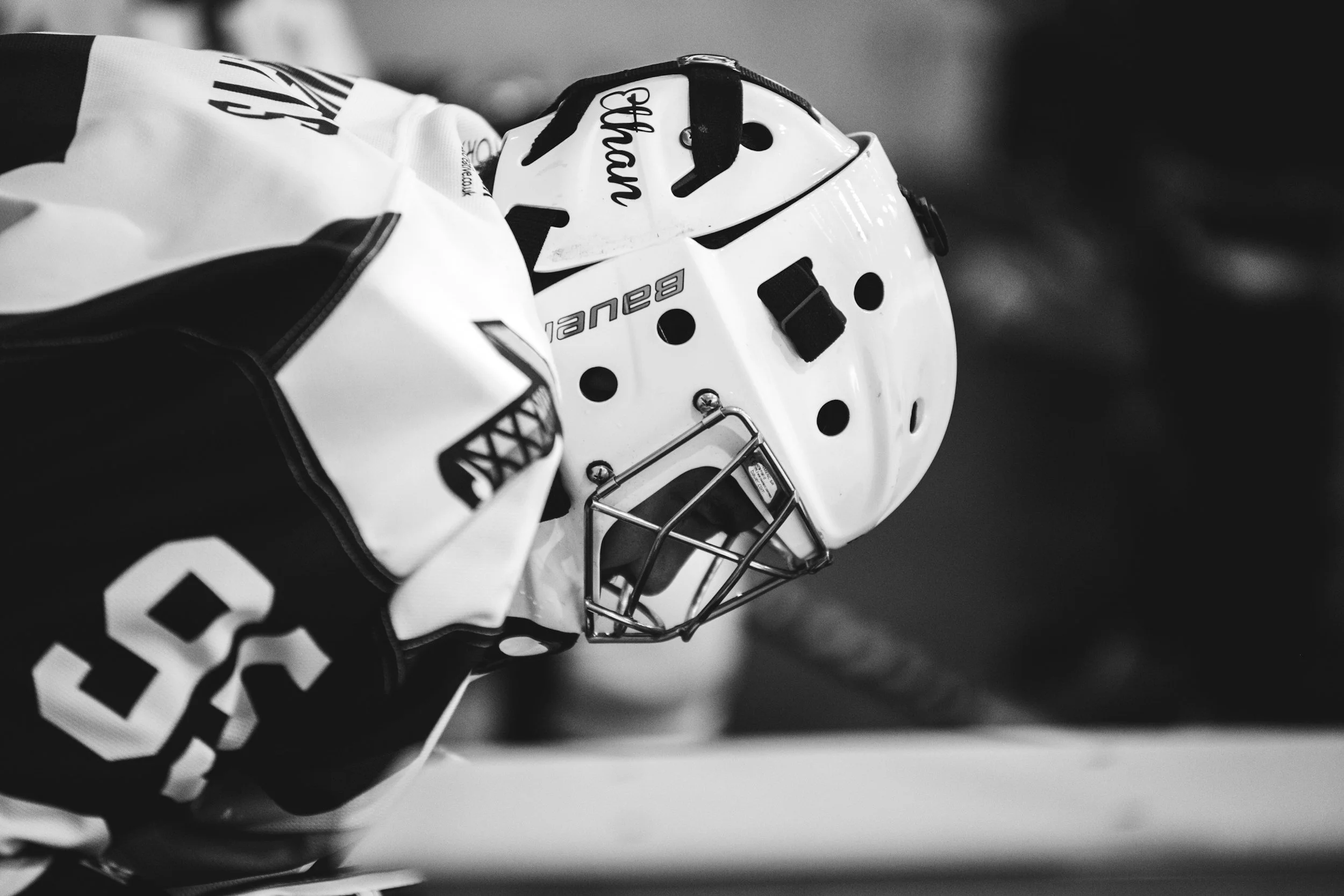 Close-up of a hockey goalie helmet and glove on the ice, black and white