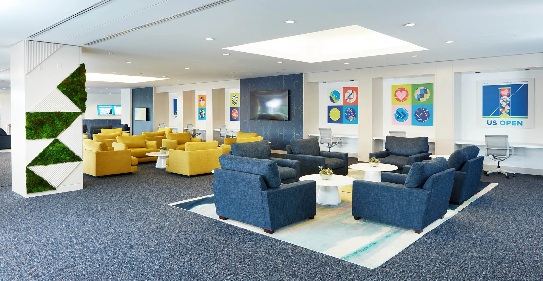 Modern airport lounge with yellow and blue chairs, white tables, greenery wall decor, wall art, and a large flat-screen TV.